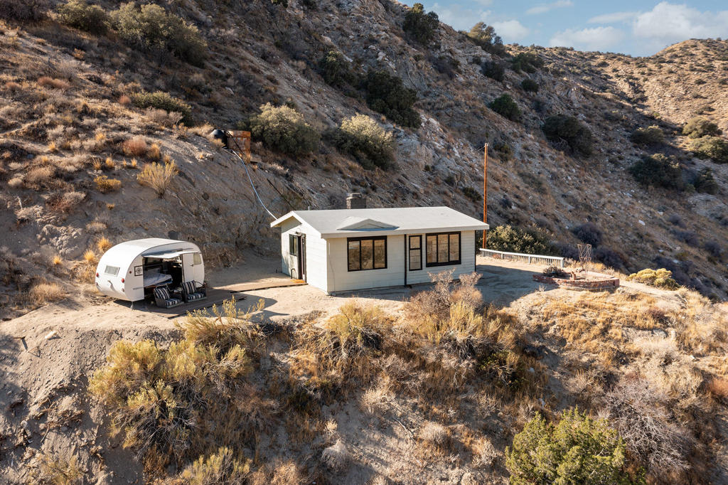 Owner Will Carry Financing! Dream cabin elevated on a hill in the clouds. Meticulously remodeled designer mid century home. Stunning natural panoramic views. 10 acres on two legal lots. Property backs up to government land that connects to the Sand to Snow Monument. Your own nature park with trails, valleys, ridges, and 360' views. Slab walkway leads to the entryway with a matte black barn light. Front door opens to the living room with a masonry fireplace, hearth ledge, gallery wall with picture light and large windows. Kitchen area with recessed lighting, butcher block island, refrigerator, stove, sink, cupboards, cabinets and countertops. Bedroom nook with inspiring vistas, shelving, ceiling fan, and breakfast bar table. Bathroom with floating pedestal sink, mirror cupboards, large walk in tile shower. Step out on the hilltop patio high above the valley. Vintage remodeled 50's trailer guest unit with deck patio and sofa chair loungers. Queen bed with cabinets and amazing views. Natural desert fauna of yucca trees, creosote bushes, and cactus. 20 miles to Palm Springs. 115 miles to LA. 21 miles to Joshua Tree National Monument. 10 miles to Yucca Valley. The local Covington Park offers tennis courts, kids playgrounds, and community center. Restaurants and amenities nearby. May qualify for Conventional Lending. Don't wait, Call Now!