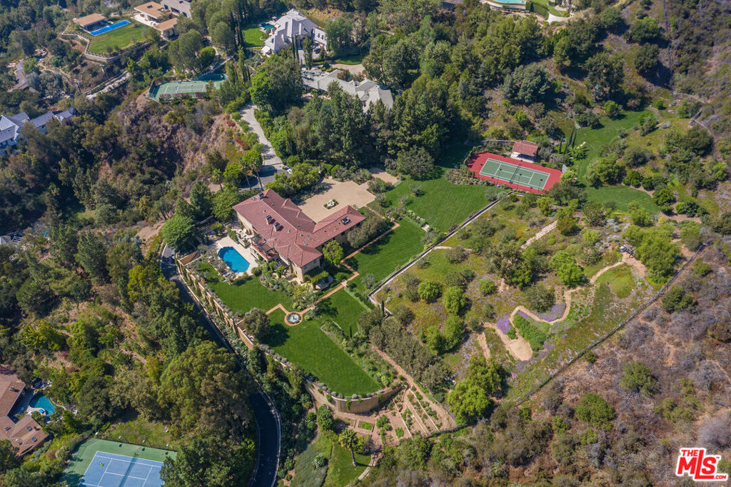Sited in a unique microclimate off lower Mandeville Canyon, The Ranch has the most magnificent gardens of any estate on the Westside of Los Angeles. Comprised of approximately *6.22 acres of verdant grounds, this most special offering guarantees complete privacy as it is surrounded by another approximate 7 acres of open space and the Santa Monica Mountain Preserve. A true world apart. Soaring gates open to an expansive motor court with ample parking for 16 cars. The main residence includes high ceilings, exquisite details and a fabulous floor plan for entertaining. A 2-story formal living room, exceptional bistro dining room with seating for 22, wood-paneled office and media room all flow seamlessly. Gourmet chef's kitchen and family room open to an outdoor dining pergola which overlooks an alley of Melaleuca trees. Totaling 6 generous bedrooms, the master suite is the ultimate retreat with sitting room, marble bath and luxurious double closets. Large playroom, sitting room and gym complete the upstairs. A basement-level auxiliary space with towering vault door entrance is sure to make a lasting impression and perfect for large meetings with state-of-the-art technology and security. The gardens at The Ranch transport you to another time and place, with acres of meadows and grass as far as the eye can see. Lavender dots the landscape and specimen trees are abundant. Outdoor activities include a championship size tennis court with pavilion, a hiking trail with view pergola and glamorous pool with cabana. An orchard containing over 20 types of fruit trees and farm-to-table vegetable and herb garden complete this unique compound. The Ranch at Rivers Road is a world-class destination unrivaled in the city.