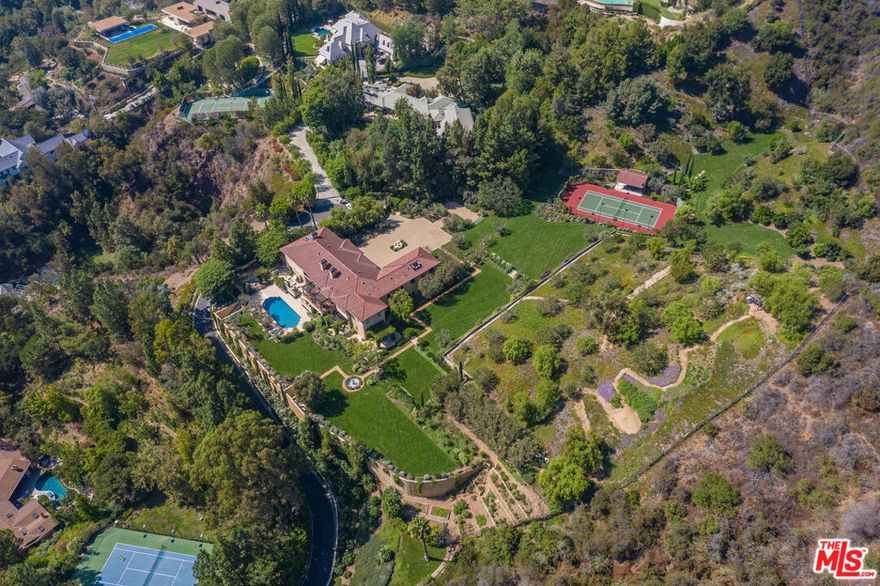 Sited in a unique microclimate off lower Mandeville Canyon, The Ranch has the most magnificent gardens of any estate on the Westside of Los Angeles. Comprised of approximately *6.22 acres of verdant grounds, this most special offering guarantees complete privacy as it is surrounded by another approximate 7 acres of open space and the Santa Monica Mountain Preserve. A true world apart. Soaring gates open to an expansive motor court with ample parking for 16 cars. The main residence includes high ceilings, exquisite details and a fabulous floor plan for entertaining. A 2-story formal living room, exceptional bistro dining room with seating for 22, wood-paneled office and media room all flow seamlessly. Gourmet chef's kitchen and family room open to an outdoor dining pergola which overlooks an alley of Melaleuca trees. Totaling 6 generous bedrooms, the master suite is the ultimate retreat with sitting room, marble bath and luxurious double closets. Large playroom, sitting room and gym complete the upstairs. A basement-level auxiliary space with towering vault door entrance is sure to make a lasting impression and perfect for large meetings with state-of-the-art technology and security. The gardens at The Ranch transport you to another time and place, with acres of meadows and grass as far as the eye can see. Lavender dots the landscape and specimen trees are abundant. Outdoor activities include a championship size tennis court with pavilion, a hiking trail with view pergola and glamorous pool with cabana. An orchard containing over 20 types of fruit trees and farm-to-table vegetable and herb garden complete this unique compound. The Ranch at Rivers Road is a world-class destination unrivaled in the city.