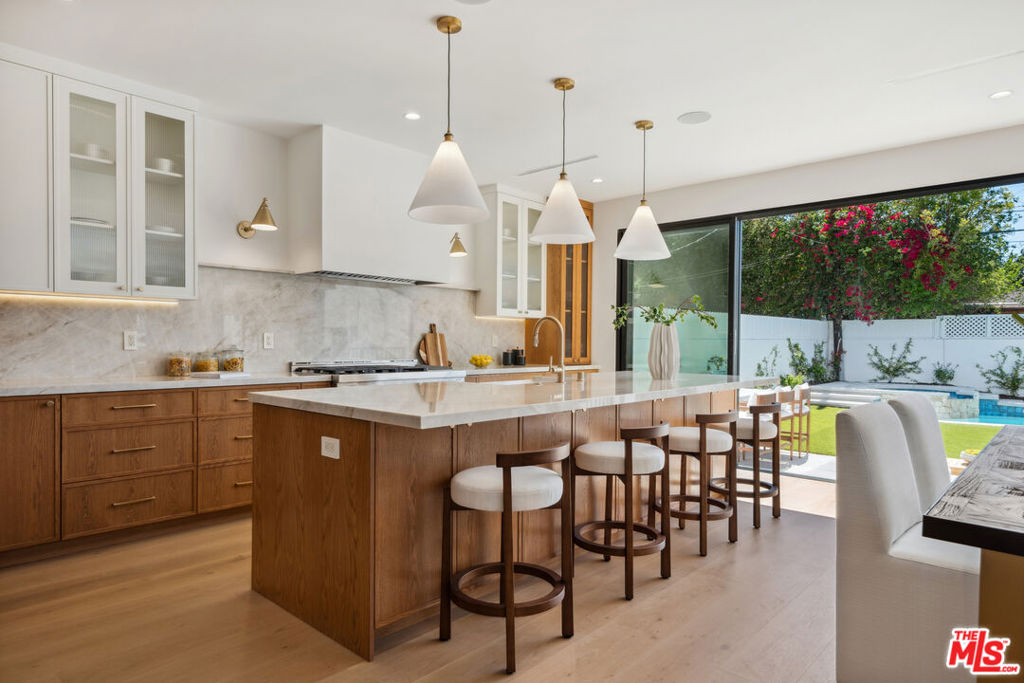 Welcome to this beautifully renovated gem nestled in the highly sought-after neighborhood of Toluca Woods. This exceptional property features a spacious 4-bedroom, 3-bathroom main house along with a fully detached 1-bedroom, 1-bathroom ADU, offering the perfect blend of design, functionality, and versatility. No detail was spared in the complete stud out renovation, showcasing custom-crafted oak cabinetry, elegant stone quartzite countertops, engineered white oak floors, designer light fixtures and high-end finishes throughout. The open-concept layout flows seamlessly, ideal for both everyday living and entertaining. The primary bedroom is draped with natural lighting with high ceilings, an en-suite designer bathroom with a perfectly situated floating tub under your bay windows. Another two bedrooms upstairs share a stunningly designed hall bathroom with dual vanity sinks and built in cabinets for linens. One last bedroom in the main house is downstairs, perfect for guests or an in home office. Step outside into your private entertainer's backyard oasis, complete with a sparkling swimming pool, ample patio space with a built-in bbq, and lush landscaping perfect for summer gatherings or tranquil evenings under the stars. The detached ADU is thoughtfully designed with its own entrance, full kitchenette, and modern amenities, making it perfect for guests, extended family, or rental income potential. Located on a quiet, tree-lined street in one of the Valley's most desirable neighborhoods, this turnkey property combines timeless style with contemporary comfort. Don't miss the opportunity to own this exceptional home in Toluca Woods.