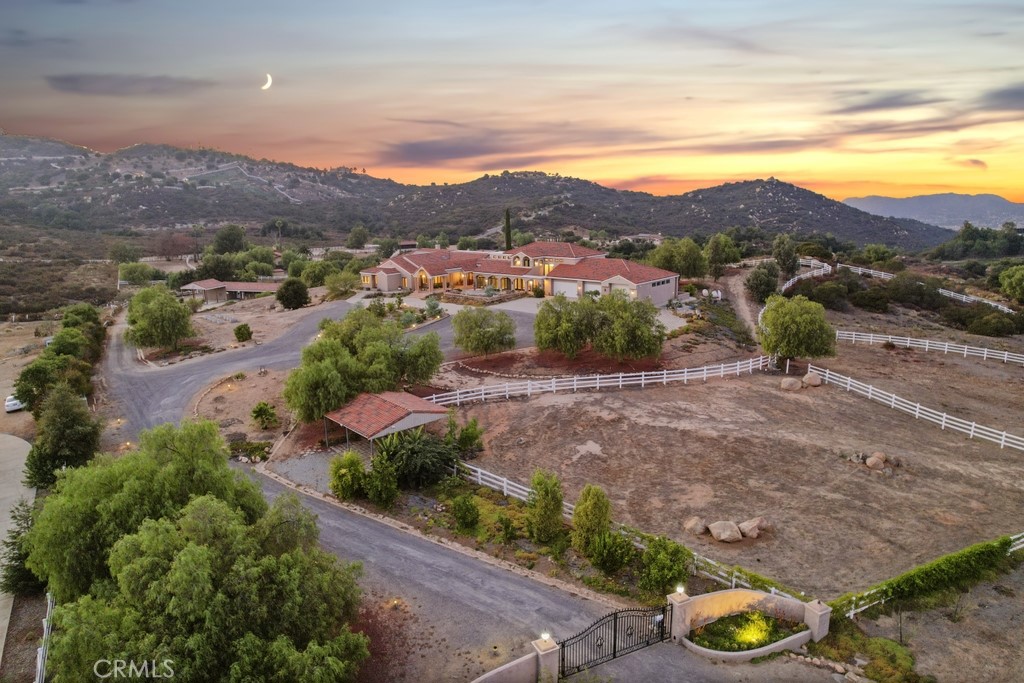Grand Equestrian Estate with Panoramic Views & Endless Possibilities in La Cresta. Set atop 5.55 breathtaking acres, this spectacular La Cresta equestrian estate offers panoramic views from every window, luxurious living spaces, and versatile additions including a studio casita and a converted caretaker home attached to the barn. A 5-stall barn, RV garage, fenced pool with view deck & outdoor kitchen, and indoor spa make this a true dream property. Enter through solid wood double doors into a stunning foyer with terra cotta tile, leading to formal living and dining rooms featuring marble floors, wood-beamed vaulted ceilings, and oversized windows showcasing majestic mountain and garden views. The grand family room impresses with a fireplace, wood floors, custom built-ins, and French doors to the patio and pool. The spacious kitchen includes granite counters, wood cabinetry, a large island, and views of the pool and mountains. A den or office, additional flex space with built-ins, and access to the spa room offer flexible living. The primary suite boasts incredible views, a fireplace, private office, outdoor access, and a luxurious en suite with soaking tub, dual vanities, and two walk-in closets. Upstairs via two staircases, find a spacious loft, 3 bedrooms, and a huge balcony. Two junior suites downstairs feature private baths and walk-in closets, plus an additional den/bedroom. The studio casita includes a full bath, walk-in closet, and kitchenette space. The attached barn unit offers a living area, kitchen, 2 bedrooms, and a bathroom—perfect for guests or caretakers. There's a leased solar system for energy efficiency. Additional adjacent 5-acre parcel also for sale on Via Baya—combine for a rare 10+ acre equestrian estate!