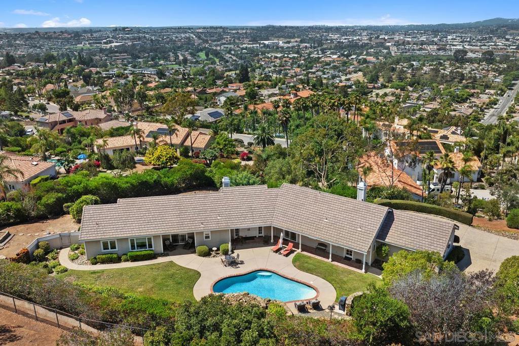 Stunning single-story home nestled on over an acre of land with a tranquil private pool and panoramic views of San Marcos and the ocean on the horizon. This beautifully maintained property features 3 spacious bedrooms, 2.5 bathrooms, and a 3-car garage, offering comfort, convenience, and exceptional amenities. Inside, you'll find vaulted ceilings, gas brick fireplaces in the family & living rooms, recessed lighting, and ample natural light. The kitchen flows seamlessly to the outdoor spaces, and is equipped with an island with storage, double oven, custom pantry, and breakfast area. The spacious primary suite is truly a retreat, featuring built-ins, seating area, an expansive custom walk-in closet, and spa-like bath with dual vanities and soaking tub. Separate laundry room includes built-in cabinetry, sink, and a dedicated ironing station. The home is equipped with central air conditioning, a whole-house alarm system, central vacuum, and an oversized coat and hallway storage closet. The garage is a standout with attic storage accessed by a pull-down ladder, an automatic opener for all three bays, and a workbench with a hot and cold water utility sink. Step outside to your private oasis, complete with a heated pool featuring waterfalls and an automatic pool sweep, plus plenty of space for a future spa or jacuzzi. The yard is fully fenced and serviced by an automatic sprinkler system. Additional outdoor highlights include a gas line plumbed for a BBQ and a custom exposed aggregate/pebble driveway and walkway. See supp. This exceptional home is ready for you to move in and enjoy — a rare opportunity to own a private retreat with sweeping views and resort-style living in San Marcos.