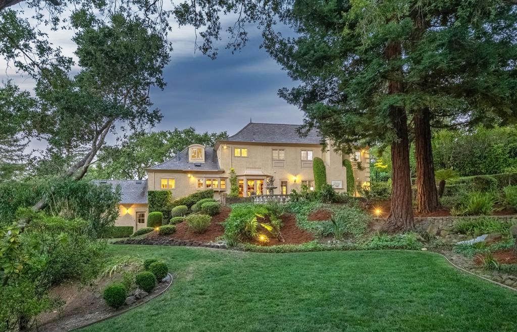 Highly desirable Platinum Triangle, this stately French Normandy estate offers extraordinary privacy and a serene setting. Manicured grounds, majestic trees, small vineyard & colorful gardens create a peaceful retreat that exudes natural beauty. A thoughtfully designed floor plan welcomes you with a soaring foyer and sweeping staircase. Bright, open formal living room with hardwood floors, large windows, and fireplace with marble surround. Family room boasts wood-beamed ceilings, large wood-burning fireplace. The gourmet kitchen offers a natural stone-topped island, ample wood cabinetry & breakfast bar. Viking Professional 4-burner range with grill & griddle, Sub Zero fridge/freezer & KitchenAid dishwasher. Breakfast nook & formal dining - ideal spaces for family meals & entertaining guests. The primary suite features built-in drawers/ shelves, plantation shutters, and luxurious bathroom with two vanities, a tiled stall shower and tub. 2 cedar walk-in closets with built-in shelves, racks, and drawers. Highlights of the home include 3 additional second-floor bedrooms (1 ensuite & 2 with shared bathroom), an ensuite ground-floor bedroom/office with built-in desk and cabinetry, a temperature-controlled wine cellar, new carpet, and a circular driveway leading to the three-car garage.