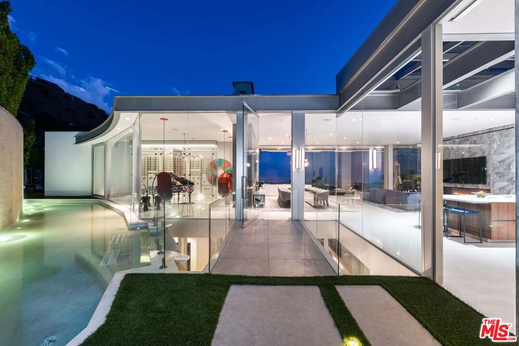 Available fully furnished turn-key for short and long-term rentals! Revel in opulence and sophistication in this ultra-private contemporary architectural marvel. Step past the reflecting pool and sculptured waterfall into the drama of 12ft high ceilings in every room. Bathe in waves of natural light as jetliner views of the Pacific Ocean shine through floor-to-ceiling glass walls that surround the living spaces. Entertaining or relaxing are second nature to the magnificent great room which boasts a floor to ceiling marble fireplace and opens onto the spectacular view terrace with 120ft infinity pool and spa. The gourmet kitchen features a butler's pantry, expansive breakfast bar, temperature-controlled wine storage, and formal dining room. The glamorous pool-side master suite with private terrace is always available for your quiet moments. This exquisite masterpiece includes a reception room with bar, luxurious screening room, game room, Harley Pasternak designed fitness studio, and office library. A true showcase, it was designed in 2016 by Paul McClean and offers you and your family and friends the greatest attention to the finest details including gallery-sized walls displaying the curated art collection. Optimally located in the Doheny Estates you will be mere moments from the famous Sunset Strip with its acclaimed dining, shopping and entertainment.