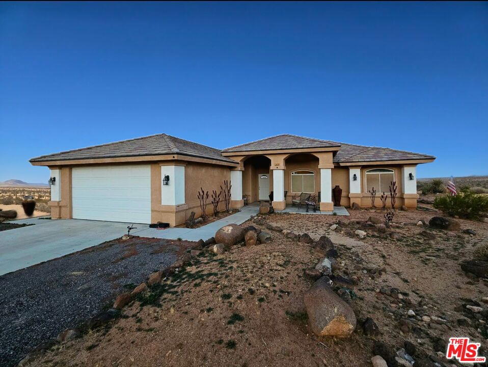 Idyllic escape to the stars and sunsets! Less than 30 miles from the delicate desert beauty of Joshua Tree National Monument. Just 20 miles from the music and art of Pioneertown. This custom-built home is 1,771 sq of thoughtfully designed ranch-construction. Energy & Tech: Paid solar (no electric bill), EV charger Layout: 3 bedrooms + den (potential 4th bedroom) Open floor plan with vaulted ceilings, recessed lighting, tile floors throughout. Living room with fireplace and French doors to back of more than 4 acres. Kitchen with stainless steel appliances, granite countertops, breakfast bar, ample cabinetry Primary Suite: Walk-in closet, double vanity, glass shower, spa tub Additional Baths: Walk-in tub, shower, and tub/shower combo Conveniences: Central AC/heat, laundry room, attached 2-car garage, tankless water heater Outdoor Features: Covered back patio, panoramic mountain/city views, 4.15-acre lot of horse property. All iron sculptures in the yard of the property are included in the sale. Potential Uses: Space for guest houses, second home, barns, horse corrals, or custom build.