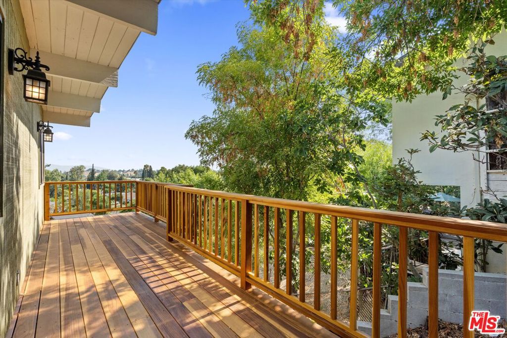 Nestled in the highly desirable "South of the Boulevard" neighborhood of Woodland Hills, this turn-key gated Mid-century Modern gem offers captivating valley to mountain views and the tranquil feel of canyon living. Signature architectural elements include the classic roofline and an iconic carport, bringing authentic mid-century character to this thoughtfully updated home.Inside, you'll find a bright and airy two-bedroom, two full bath layout with soaring wood beam ceilings and an open-concept living, dining, and kitchen area, all perfectly positioned to showcase stunning vistas.The spacious kitchen features wood-style cabinetry, granite countertops, a breakfast bar, a large walk-in pantry, and appliances including a full size refrigerator and gas range. The generous primary suite includes a large bedroom with a custom walk-in closet and a spa like en-suite bathroom complete with double sinks, a sizable shower, and a soaking tub. The second bedroom also boasts a walk-in closet and access to a private side yard patio, ideal for quiet relaxation. Step out onto the recently reinforced deck to take in panoramic views while enjoying your morning coffee or an evening drink. Below, the expansive, undeveloped yard offers privacy and a natural setting to enjoy from above. Located within a top-rated school district and just minutes from the beach, 101 freeway, and an array of premier shopping, dining, and entertainment spots, including Topanga Canyon, Ventura Blvd, The Commons at Calabasas, Old Town Calabasas, Serrania Park, Westfield Topanga, and Topanga Village. Enjoy nearby hiking trails and parks while living in one of Woodland Hills' most sought after enclaves. Opportunities to lease a home with this level of charm, privacy, and location are rare. With breathtaking views and timeless design, this exceptional Woodland Hills residence won't be available for long, schedule your showing today.
