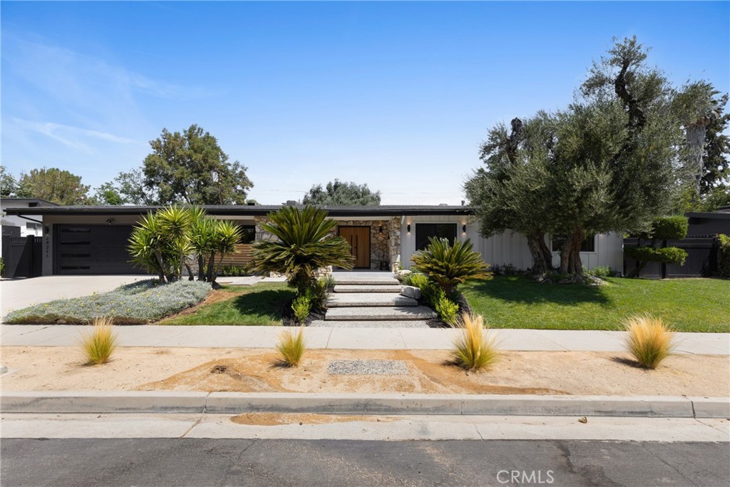 Nestled on a tranquil tree-lined Street, this masterfully restored, single-story Charles Dubois home offers an unparalleled living experience. Located in one of the most highly desirable Woodland Hills neighborhoods of Woodland Hills , you'll enjoy close proximity to award-winning schools, exceptional shopping and entertainment at The Village, The Commons in Calabasas, and some of the best restaurants around. From the graceful entry adorned with mature trees to the alluring zen-like yard “with Mountain View’s “ this home embodies true California living. With an extensive high-end renovation in 2025, this residence has been carefully restored and transformed into a chic and stylish showstopper with Lots of Curb appeal , seamlessly blending Modern design with modern comforts. Upon entering, you are greeted with the interior Foyer living area featuring Open Spacious Floor plan and a cozy Art piece Mid Century Modern fireplace, and an amazing view of the lush front yard with its brand new, Remodeled pool and Lounge area perfect for year-round entertaining. The interior is thoughtfully arranged with open living and dining spaces in mind. The newly remodeled kitchen, complete with European-style custom wood cabinets and a stunning center island “ Chefs Kitchen” provides the perfect setting for entertaining. Adjacent to the kitchen is an expansive dining room with a fireplace, large windows, and sliding doors that lead to the breathtaking backyard oasis. This home also features a large family room and Custom Wine room area holding up to 52 bottle creating an ideal space for casual gatherings. The Living and Dining rooms open directly to the backyard, enhancing the indoor-outdoor flow. In the backyard, you'll find a custom-built Large Patio with a dining area inside, perfect for alfresco meals. The backyard also boasts a Large freshly laid Sod Grassy yard with ample space for relaxation or entertaining. There are four bedrooms with on suites for each bedroom including the primary suite, which features an exquisite bath, custom tiles and a custom built walk-in His/ Hers closets and and Sliding door that open to the Pool & Lounge area and enjoy a great view of the gorgeous pool & Mountains views Tranquil and very private backyard with custom barbecue and entertainment area. Don’t miss your Chance to make it yours!