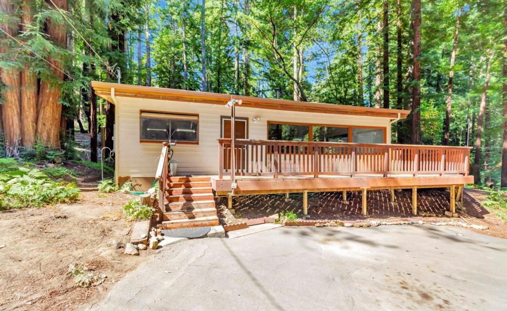Welcome to your redwood retreat! This charming 2-bedroom, 1-bath home offers 1,081 sq ft of light-filled living space surrounded by towering trees and natures serenity. Step inside to an open floor plan with wood-beamed ceilings, laminate floors, and large windows that bring the outdoors in. A cozy wood stove adds warmth to the spacious living area, perfect for relaxing evenings. The kitchen is functional and inviting, with a walk-in pantry for extra storage. Both bedrooms are comfortable, with the primary featuring a skylight that fills the room with natural light. Step outside to a generous wraparound deck, ideal for outdoor dining, morning coffee, or simply enjoying the peaceful forest views. An elevated storage shed adds rustic charm and practical space. Located on a quiet street, this home is a true escape, yet just minutes from downtown Boulder Creek. Enjoy a close-knit community with endless opportunities for hiking, biking, and exploring the surrounding natural beauty. Whether you're seeking a weekend getaway or a place to slow down and unwind, this property offers the perfect balance of comfort,and connection to nature.