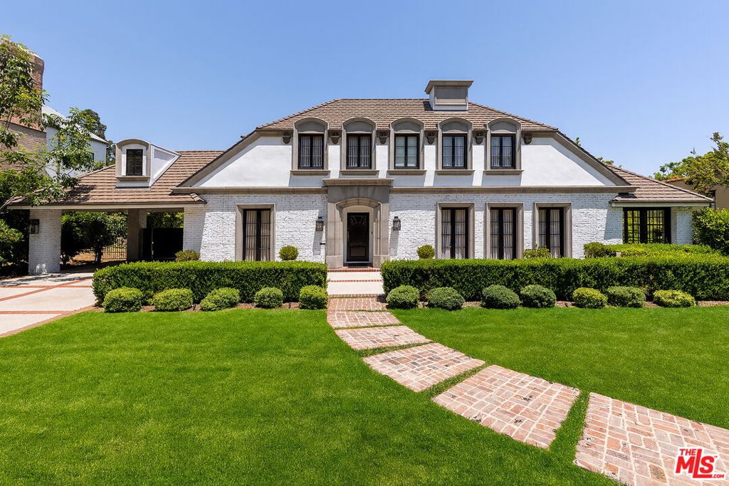 Stunning and fully remodeled traditional estate on almost half an acre in the heart of Beverly Hills Flats, offering 6 beds, 6 baths, and approximately 6,200 sq ft of elegant living space. The main house showcases a true chef's kitchen, a luxurious primary suite with salon sink, expansive closets, spa-like bath, and state-of-the-art amenities throughout. Retractable glass doors open the family room to a lanai that seats 22, seamlessly blending indoor-outdoor living with a lushly landscaped yard, pool, and spa- ideal for entertaining. Five en suite bedrooms in the main residence plus a beautifully renovated guest house with kitchenette, laundry, and bath complete this private oasis. A rare offering on one of the most sought-after streets in Beverly Hills.