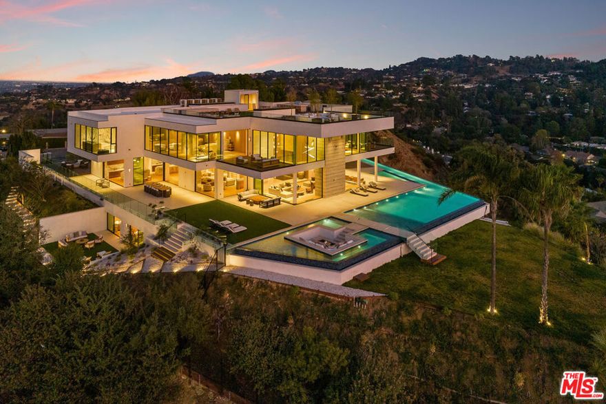 Discover 16187 Royal Oak Rd, a bold fusion of luxury, design, and unparalleled views in Encino's most sought-after enclave. This contemporary estate, set on nearly two acres, delivers a lifestyle of sophistication and tranquility. From the moment you step through the grand pivot door, you're greeted by open spaces, dramatic ceilings, and panoramic city and canyon vistas through walls of glass. The heart of the home is a chef's kitchen that seamlessly flows into living and dining areas, designed for effortless entertaining. Step outside to your private oasis, complete with an infinity pool, spa, and ample lounging space all framed by lush, secluded landscaping. With 8 bedroom suites, 11 baths, a state-of-the-art home theater, wine cellar, gym, and spa, every inch of this home is crafted for comfort and style. The primary suite is its own retreat, featuring a private terrace, and a spa-like bath. Come and experience an estate where exceptional design and serene beauty meet, creating a living experience like no other.
