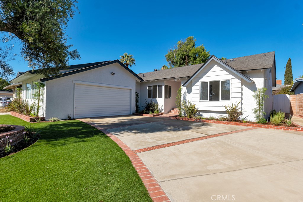 This fully reimagined Granada Hills residence is a rare find—blending modern luxury with timeless style in one of the area’s most desirable neighborhoods. From the moment you arrive, the home makes a statement with fresh exterior paint, a wide concrete driveway with brick inlay, lush new synthetic turf, mature privacy trees, and a sleek new cool shingle roof. Step inside to an expansive open layout with approximately 1,875 sq. ft. of beautifully curated living space. The home features 3 spacious bedrooms and 3 elegantly renovated bathrooms, each designed with meticulous attention to detail. At the heart of the home, the brand-new chef’s kitchen impresses with custom maple cabinetry, soft-close drawers, crown molding, and under-mount cabinet lighting. Premium quartzite counters with a full backsplash, new GE stainless steel appliances, a farmhouse sink, luxury vinyl flooring, and a breakfast counter complete the space. An adjacent dining area and separate laundry room—with full pantry, custom cabinetry, quartz counters, and utility mop sink—add convenience and style. Two living spaces cater to every occasion: a spacious family room with direct access to the entertainer’s backyard, and a cozy living room anchored by a gas fireplace with a stone hearth and custom mantel.The flexible floor plan boasts two primary suites. The main retreat is a true sanctuary with a new spa-like bathroom showcasing an oversized walk-in shower, perfect for sharing, with multiple showerheads: fixed, handheld, and rainfall, a separate soaking tub, floating vanity with quartzite counters, porcelain flooring and a private water closet. The second suite offers its own new bathroom with an expanded shower, custom vanity, and linen storage. A third bedroom and chic full hallway bath complete the interior. Throughout the home, thoughtful upgrades abound: wide-plank luxury vinyl flooring, crown molding, 6-inch baseboards, new 5/8" thick paneled doors and double-pane windows both with custom casings, new paint inside and out, recessed lighting throughout, updated copper plumbing, newer HVAC, modern thermostat, and an attached two-car garage. Step outside to a private backyard retreat featuring new synthetic grass, mature landscaping, raised brick planter beds with drip irrigation, and plenty of room to relax or entertain. Perfectly located near parks, top schools, shopping, and major freeways—this is more than a home, it’s a lifestyle upgrade.