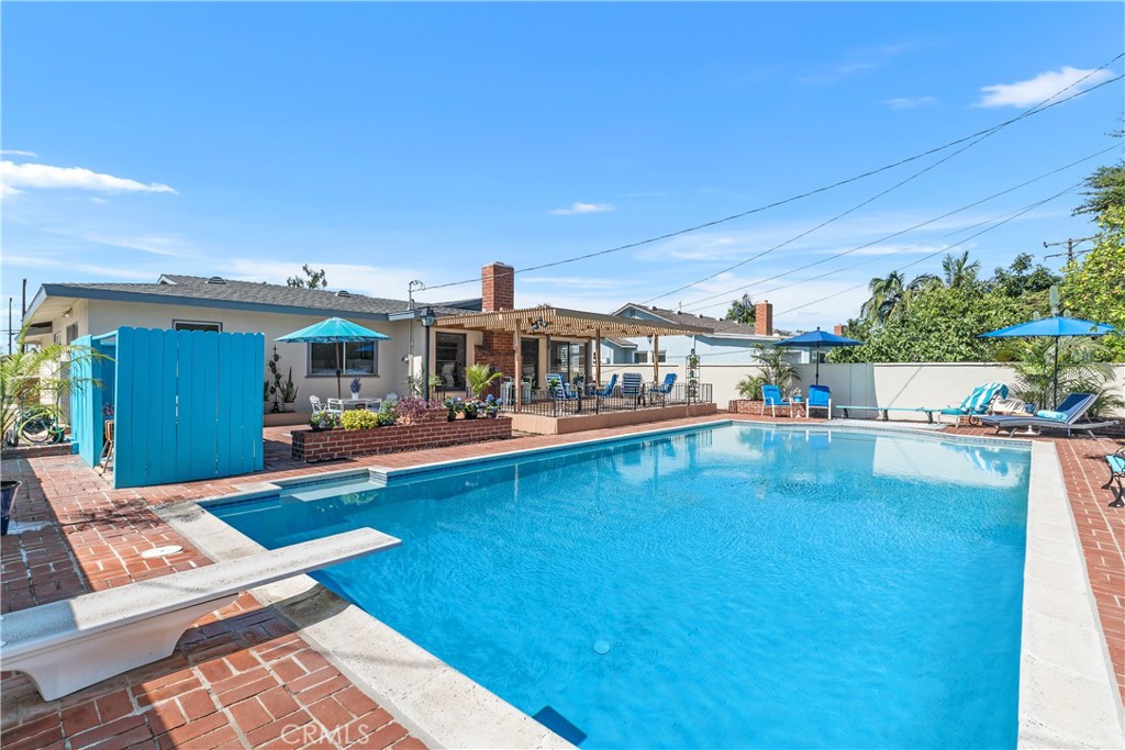 This property has not been on the market in 60 years! An exceptionally large and deep swimming pool with a diving board, is the highlight. The pool is surrounded with hand laid bricks and wrap-around planters bordering the pool and patios. It's easy to embrace life al fresco on the covered deck where everyone naturally gravitates. This outdoor space has been the gathering place of four generations providing happiness and good times.
All-natural hues are just the right backdrop for the easy flow single level home. The kitchen has real wood flooring and cabinets; a built-in wood banquette, windows have wood casings and widened wood doorjambs. The living room has a wood burning fireplace and the view looks out over the deck and pool. There is also sq. ft. added (not added in the sq ft total) off the dining room for a sunny place to work from home. In addition, off the primary bedroom, there is a lot of space in the yard possibly for another bathroom? (verify with the city) The kitchen has reverse-osmosis filtration system and a new dishwasher. There are new commodes, new landscape, all new screens and the garage has been freshly painted. The original driveway has been widened, both side yards are oversized. One is fully cemented and the other partial cemented with stepping-stones for easy maintenance. There are timed sprinklers in the front yard. The home has been well loved and has a binder of past upgrades and receipts of the home's maintenance. Located in Northeast Anaheim, this property is in a prime location and approx. 22 miles to Newport Beach! The city boasts a Mediterranean climate, allowing for year-round activities and is centrally located for easy access to all the wonderful So. Cal destinations.