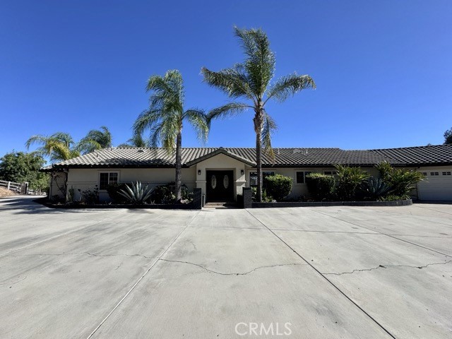 This expansive 3 bedroom, 3 bathroom estate perfectly blends luxury and country living in the heart of Temecula’s Wine Country. Set on nearly 2.5 acres, the property offers a resort-style Pebble-Tec pool and spa, 4 horse stables, a large patio deck, and a 4 car garage, designed to deliver both relaxation and entertainment. The long, tree-lined driveway makes a striking first impression. Enter inside to find plank flooring, abundant natural light, and stunning upgrades throughout. The chef’s kitchen is a true centerpiece with quartz countertops, a custom wood ceiling, stainless steel appliances, ample storage, and generous prep space. Seamlessly opening to the family room and dining area, it creates the ideal setting for gatherings. Just off the kitchen, the laundry room comes equipped with a washer, dryer, sink, and extra storage for added convenience. Down the hallway, spacious secondary bedrooms and updated bathrooms provide comfort and style, along with direct garage access. The primary suite, located just off the entry, is a private retreat complete with a cozy fireplace, sitting area, dual sliding doors leading to the backyard, and a spa-like ensuite featuring a freestanding soaking tub, walk-in shower, dual vanities, and a large custom walk-in closet. Outdoors, the property transforms into a private oasis. Relax on the covered porch, gather around the firepit, or lounge poolside while taking in the serene surroundings. Landscaping with quarterly weed abatement and pool service are both included. Horses are welcome and encouraged with facilities and a trailer hookup pad available for use in “as-is” condition if accessible from the main driveway. Please note that the second and third gates along Via Broza are restricted due to easement limitations, residents must use the main entrance. Surrounded by Temeculas wineries, top rated schools, and just a short drive to shopping, dining, and parks. Dont miss your opportunity, schedule your private showing today!