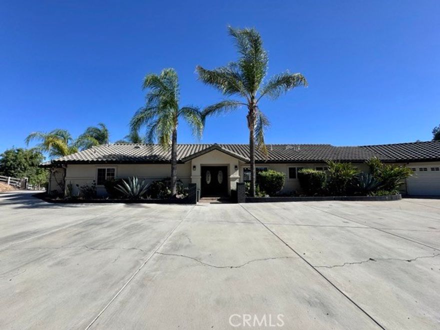This expansive 3 bedroom, 3 bathroom estate perfectly blends luxury and country living in the heart of Temecula’s Wine Country. Set on nearly 2.5 acres, the property offers a resort-style Pebble-Tec pool and spa, 4 horse stables, a large patio deck, and a 4 car garage, designed to deliver both relaxation and entertainment. The long, tree-lined driveway makes a striking first impression. Enter inside to find plank flooring, abundant natural light, and stunning upgrades throughout. The chef’s kitchen is a true centerpiece with quartz countertops, a custom wood ceiling, stainless steel appliances, ample storage, and generous prep space. Seamlessly opening to the family room and dining area, it creates the ideal setting for gatherings. Just off the kitchen, the laundry room comes equipped with a washer, dryer, sink, and extra storage for added convenience. Down the hallway, spacious secondary bedrooms and updated bathrooms provide comfort and style, along with direct garage access. The primary suite, located just off the entry, is a private retreat complete with a cozy fireplace, sitting area, dual sliding doors leading to the backyard, and a spa-like ensuite featuring a freestanding soaking tub, walk-in shower, dual vanities, and a large custom walk-in closet. Outdoors, the property transforms into a private oasis. Relax on the covered porch, gather around the firepit, or lounge poolside while taking in the serene surroundings. Landscaping with quarterly weed abatement and pool service are both included. Horses are welcome and encouraged with facilities and a trailer hookup pad available for use in “as-is” condition if accessible from the main driveway. Please note that the second and third gates along Via Broza are restricted due to easement limitations, residents must use the main entrance. Surrounded by Temeculas wineries, top rated schools, and just a short drive to shopping, dining, and parks. Dont miss your opportunity, schedule your private showing today!