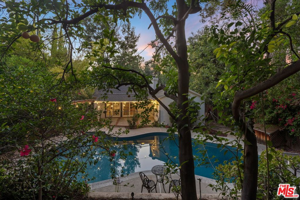 Welcome to this charming single-story ranch home nestled South of Ventura Blvd in the heart of Woodland Hills. This 3-bedroom, 2-bathroom residence offers over 1,250 sqft of bright, open living space situated on an expansive 11,000+ sq ft lot. Designed for easy California living, the open-concept layout features two sets of sliding glass doors that seamlessly connect the indoor living areas to the lush backyard. The spacious primary suite offers direct access to the outdoors, creating the perfect retreat. Enter outside and unwind beneath the covered patio, ideal for al fresco dining or lounging poolside. The recently resurfaced large swimming pool is surrounded by mature fruit trees and thoughtfully tiered landscaping, offering multiple spaces for play, gardening, or even a private storage area. Whether you're looking to entertain, relax, or reimagine the outdoor potential, this home offers endless possibilities in one of Woodland Hills' most desirable pockets.