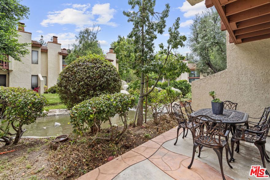 Move-in-ready townhome in the highly desirable Warner Center of Woodland Hills, where nature, comfort, and convenience meet. The updated kitchen with stainless steel appliances opens directly to the living room, which features a cozy fireplace and sliding doors to a private patio, the perfect spot to enjoy peaceful moments with the gentle sound of flowing water and nature. A guest bathroom is located downstairs for everyday convenience. Upstairs you'll find two bedrooms and a full bathroom with a shower, the primary suite offer its own separate vanity with sink. Vaulted ceilings give the home an open, airy feel, and a private balcony off the primary suite adds fresh light and breezes. Additional features include in-unit stackable laundry, central heat and air, and beautiful flooring throughout. Parking is a breeze with one space in the shared garage, an assigned spot located right in front of the unit, and plenty of guest parking nearby. This community offers true resort-style living with ponds, a pool, jacuzzi, sauna, and two tennis courts.