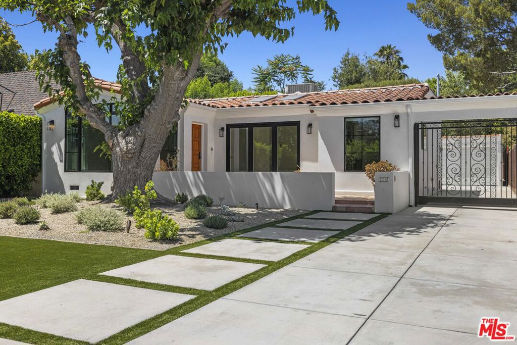 Welcome to this exquisitely reimagined 1920s Toluca Lake Spanish with a detached guest house. This beautiful residence captivates with timeless curb appeal complete with lush greenery, a gated driveway, and a patio shaded by mature trees, creating a serene and private entry. The main house welcomes you with a grand formal living room, showcasing oversized picture windows that bathe the space in natural light, elegant coved ceilings, and a charming brick fireplace with a classic mantel. An arched passage leads to the formal dining room overlooking the verdant front yard and flows effortlessly into the bright kitchen. The chef's kitchen boasts a brand new appliance package, cabinetry, and spacious countertops. The generous primary suite offers direct backyard access and a private bathroom thoughtfully updated with meticulous attention to detail. The generous guest bedroom includes a cozy sitting nook, sliding doors opening to the backyard, and a beautifully updated ensuite bathroom. Step outside to an inviting large deck beneath cafe lights- an ideal setting for entertaining and al fresco dining during warm evenings. Additional amenities include a convenient laundry room adjacent to the kitchen, a detached two-car garage with a private driveway, and secure storage space. Complementing the main home, the detached back house offers a versatile 2-bedroom, 1-bathroom layout perfect as a guest retreat or office complete with a private patio and laundry. Located in the coveted Rio Vista School District and just moments from Tujunga Village and Toluca Lake Village, this unique property delivers an exceptional blend of classic character, modern upgrades, and flexible living in one of the area's most desirable neighborhoods. Welcome home!