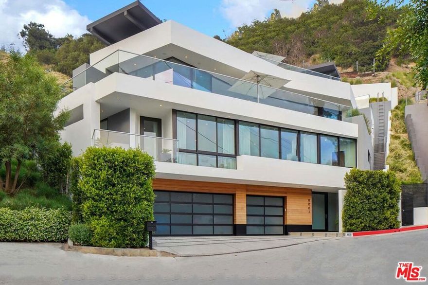 A striking architectural Contemporary privately gated just above the Sunset Strip with an impressive rooftop and pool overlooking the city lights. Boasting 3 spacious en-suite beds and 6 baths with elevator access to all floors and rooftop deck, this home was built with meticulous craftsmanship and bespoke finishes throughout. Enter through the oversized pivot door into the grand entry leading to the luxurious home theater and floating Oak stairs. The upper level features floor-to-ceiling glass doors that lead to the extensive deck with city and ocean views, as well as skylights that saturate the home with a plethora of natural light. The chef's designer kitchen is replete with a large stone island, Miele appliances, espresso machine, and double built-in wine coolers. The primary suite features a resort-style bathroom dressed in Calcutta marble, double vanity sinks, an oversized steam shower, a floating ceiling above the spa-like tub, and a beautifully equipped walk-in closet. Experience quintessential California living on the spectacular rooftop with pool, lounge area, full bath, and built-in BBQ. A separate gated grassy area is perfect for a dog run or gardening. 3-car attached garage with additional exterior parking. Truly an unrivaled offering in the Hollywood Hills given its size, scale, quality, and amenities.