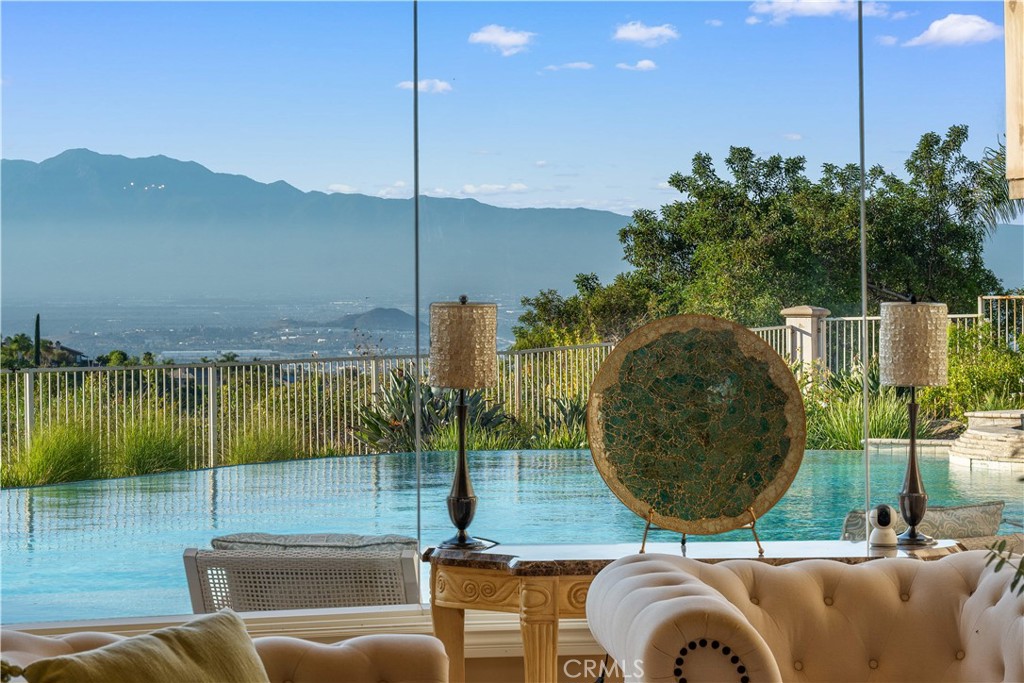 Welcome to PARADISE~!~ This hidden gem is a masterfully crafted private estate—custom-designed, discreetly luxurious, and truly unique. You will not find this level of quality and attention to detail in any of the semi-custom homes in Corona. Upon entry, custom floor-to-ceiling glass walls immediately capture sweeping views of the city and surrounding mountains—an awe-inspiring panorama that sets the tone for the entire home. This estate features five large bedrooms each with its own bathroom, with custom guest suite can be your 6th bedrooms. A private office on second floor with sweeping views of the beautiful cityscape offers the perfect space for work or quiet reflection. The heart of the home lies a chef’s kitchen—a true culinary haven featuring top-of-the-line stainless steel appliances, sleek granite countertops, a spacious walk-in pantry, and an expansive center island. Both highly functional and visually striking, this kitchen seamlessly flows into the open-concept family room, perfect for both everyday living and effortless entertaining, built in eaves provide shade for decking around stunning oversized infinity pool with breathtaking city lights and mountain views, completely private, fully gated with state of the art electronic system, impeccable landscaping, 4 car garages, no association and lower tax rate.