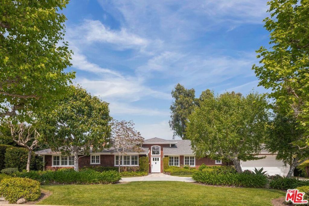 Tucked in the prestigious Riviera enclave of Pacific Palisades, this rare single-level Nantucket-style estate spans 5,011 square feet of refined living space on nearly half an acre of exquisitely landscaped grounds. Moments from the iconic Riviera Country Club, this residence offers the ideal blend of coastal elegance, privacy, and seamless indoor-outdoor living. Secluded by lush foliage, the home's classic shingle-clad exterior opens to interiors filled with natural light, soaring vaulted and beamed ceilings, and an effortless sense of space and serenity. Designed for both grand-scale entertaining and intimate daily living, the layout artfully separates public and private spaces across a thoughtful single-story floor plan. Formal living and dining rooms welcome you off the entry, framed by French doors that open to the picturesque backyard. A chef-inspired kitchen adds convenience, featuring a generous center island, Sub-Zero refrigerator, double Viking ovens, warming drawer, and a gas range. The kitchen flows into a family room with a fireplace and a sunlit breakfast nook that invites casual gathering and conversation. The home has five spacious bedrooms and 5 bathrooms, inclusive of an expansive primary suite where a fireplace lounge and direct access to the patio create a true sanctuary. The spa-like en suite boasts dual vanities, a soaking tub, a shower with bench seat, and dual water closets, all flanked by two large walk-in closets with custom cabinetry. Other notable features include the dedicated home office, laundry room, powder room, and abundant parking with the attached two-car garage and pull-through motor court. In the backyard, sprawling flat lawns, a wide entertaining patio, and a tranquil water feature set the scene for serene mornings and lively gatherings. Here, the scale and seclusion inspire dreams of creating a resort-like setting with plenty of room to add a pool, spa, sports court, and more! With its timeless design, ideal single-level layout, and premier location just minutes from Brentwood boutiques and restaurants, Palisades Village, and the coast, this exceptional residence offers an unparalleled opportunity to live with ease and coastal sophistication in one of the Westside's most sought-after neighborhoods. Offer deadline set for Monday, May 19 @ 12:00pm.