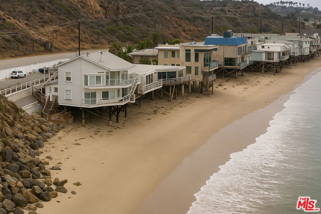 This beach house sits right on the sand, where floor-to-ceiling windows in the living room, dining area and bedrooms frame west-facing ocean views and fill every room with sunlight all day. In the living room, a bar and fireplace create a cozy focal point for effortless entertaining. The kitchen is laid out for practical use and flows seamlessly into the great room. Above the main level, a large loft provides flexible space and abundant storage. With R2 zoning, the home includes a fully equipped second kitchen, complete with its own dining and sitting area plus a private deck entrance, perfect for catering events or guest quarters. The primary suite opens onto a private beachfront deck and includes a spa-style bath with dual vanities. Two additional bedrooms each enjoy their own beachfront decks and unobstructed ocean vistas. Stairs lead you straight down to a private sandy beach, one of only 20 homes with such direct access. Anchored on reinforced pilings and backed by nearly $900,000 in marine-grade improvements, the home rests on a solid foundation that provides peace of mind. A+ water rating ensures exceptionally clean seas that draw dolphins, seals, and seabirds daily. From fishing and diving to kayaking, paddle-boarding, kite-surfing or jet-skiing, the ocean is your playground, capped each evening by sunsets stretching from the Channel Islands to Catalina. With Malibu's premier restaurants a scenic drive away on the Pacific Coast Highway, this home embodies Malibu's iconic beachfront coastal living.