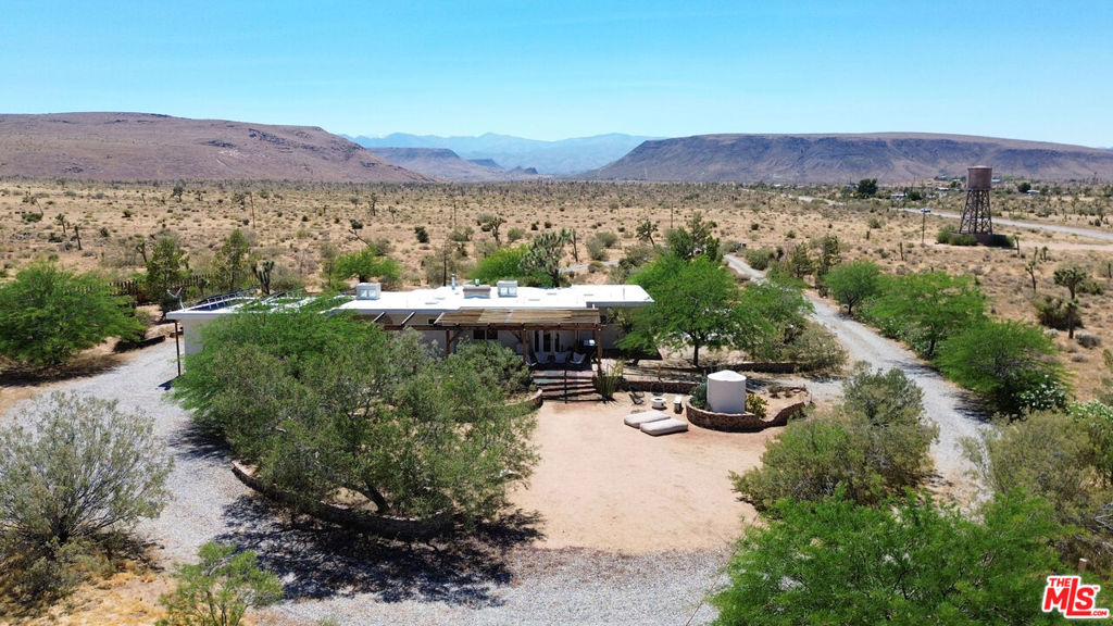 Welcome to your desert oasis! Situated on over four private and lush acres and boasting unobstructed views of Pipes Canyon, this tranquil and secluded property is truly unique in the high desert. Enjoy spectacular sunsets and starry night skies in a magical landscape filled with mature trees including Joshua Trees, mesquites, and pines. The property is centrally located just a 15 minute drive from Joshua Tree National Park, 10 minutes from Yucca Valley, and 15 minutes from Pioneertown.The house includes 3 large bedrooms, 2 baths, and is offered fully furnished with high-end pieces from Acme 5 and West Elm. Filled with unique spaces for meditation and relaxation, the house also includes two fireplaces and a large two-car garage/art studio with a half bath. The front yard features a hot tub overlooking Pipes Canyon and a cowboy soaking tub. The expansive backyard is perfect for entertaining and includes a large covered patio with dining table, plumbed-in gas fire pit and BBQ, and a dedicated RV parking area with power. This home has been a Superhost listing with over 50 five-star ratings on Airbnb.3 large paintings 2 in master and 1 in dining area are excluded from furnishings.