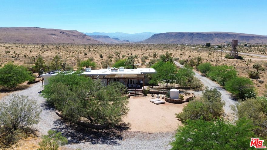 Welcome to your desert oasis! Situated on over four private and lush acres and boasting unobstructed views of Pipes Canyon, this tranquil and secluded property is truly unique in the high desert. Enjoy spectacular sunsets and starry night skies in a magical landscape filled with mature trees including Joshua Trees, mesquites, and pines. The property is centrally located just a 15 minute drive from Joshua Tree National Park, 10 minutes from Yucca Valley, and 15 minutes from Pioneertown.The house includes 3 large bedrooms, 2 baths, and is offered fully furnished with high-end pieces from Acme 5 and West Elm. Filled with unique spaces for meditation and relaxation, the house also includes two fireplaces and a large two-car garage/art studio with a half bath. The front yard features a hot tub overlooking Pipes Canyon and a cowboy soaking tub. The expansive backyard is perfect for entertaining and includes a large covered patio with dining table, plumbed-in gas fire pit and BBQ, and a dedicated RV parking area with power. This home has been a Superhost listing with over 50 five-star ratings on Airbnb.3 large paintings 2 in master and 1 in dining area are excluded from furnishings.