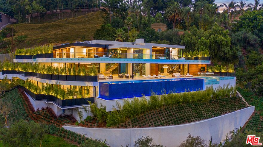 In a quiet neighborhood minutes from the heart of Beverly Hills sits 1300 Beverly Estate Dr., a 3-story retreat that captures panoramic views of the city below and ocean beyond. Designed by Lorenzo Cascino of design firm Visionnaire, this 12,500-square-foot home is filled with distinctive amenities and bespoke decorative elements. Enter the lower level from the terrace, which runs the length of the homes view-facing facade. This floor encompasses a game room, fitness studio, a 600-bottle wine wall and theater. The homes main level features a showroom garage, chefs kitchen and living areas. On the third level are 3 ensuite bedrooms and master suite. Additional features include an 80-foot-long infinity pool, motor court and smart home technology system. Located minutes from the entertainment of West Hollywood, 1300 Beverly Estate Dr. is an architectural marvel ideal for entertaining and sophisticated everyday living.