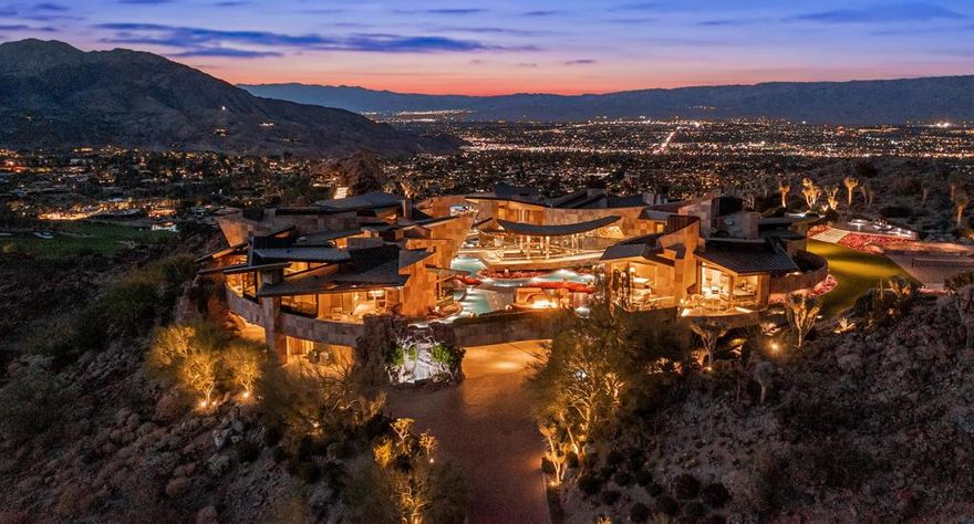 One of the most spectacular estates ever built.  Unparalleled  in size, scale and design. Organically constructed into a summit hilltop, which can not be duplicated. Surrounded by pools of oscillating water offering staggering mountain and valley views from every room.  Created by renowned architectural designer Guy Dreier and was Robb Report's Ultimate Home of the Year. Retractable walls of glass create the quintessential indoor outdoor living. Mirroring the natural terrain, the home features overlapping planes and serpentine walls forming asymmetrical pavilions. The focal point of the living room is a massive titanium-clad fireplace and ceiling of undulating wood panels. A Dale Chihuly sculpture accentuates the beauty of the room. Meander to the gracious dining room through an impressive aquarium tunnel, comprised of 2 tanks of exotic fish and a rare shark tank. The owner suite is reminiscent of the finest resorts in the world, complete with panoramic views, outdoor lounge area, private outdoor spa, fireplace and dual baths and closets. The main residence has an additional suite plus staff quarters. The guest pavilion contains four expansive bedroom suites, kitchen and lounge areas. The infamous private office is perched high into the rock and sits on a plateau with unobstructed views of the valley below. Three interlocking sculptural pools offer a one-of-a-kind swimming experience. This  property has no equal. Own your own private resort within BIGHORN Golf Club.