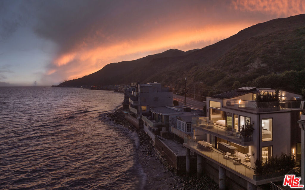Experience the pinnacle of contemporary beachfront living in this stunning, newly constructed home, where every detail has been thoughtfully designed to maximize comfort and capture breathtaking ocean views. Completed in 2022, this architectural masterpiece showcases steel-frame construction, cutting-edge smart-home technology, and approximately 57 feet of prime beach frontage. Perfectly positioned between Santa Monica and the Malibu Country Mart, this property offers both seclusion and convenience.The main floor boasts a seamless, open-concept layout where the living, dining, and kitchen areas merge effortlessly. Panoramic views are framed by vanishing glass walls, and an ultra-modern fireplace adds a touch of sophistication. A striking wine display, wraparound windows, and a wall of fully retractable Fleetwood doors extend the living space onto a spacious oceanfront deck, ideal for outdoor dining and relaxation. The kitchen is a chef's dream, featuring a vast stone-topped island with bar seating, custom cabinetry, and top-of-the-line Miele appliances.Ascend the elegant wood staircase, which offers picturesque mountain views, to the upper floor. Here, three luxurious bedrooms await, each appointed with wide-plank walnut flooring, Italian leather-lined closets, and spa-like bathrooms crafted from natural limestone. The primary suite is a true sanctuary, featuring soaring double-height ceilings, a cozy fireplace, a versatile yoga or office loft, and an expansive private deck overlooking the ocean. The ensuite bathroom is a work of art, offering a serene spa experience.The crown jewel of this residence is the rooftop deck, designed for ultimate relaxation and entertainment. With marine-grade appliances, a sleek hot tub, a fire pit, and 360-degree views, this space is perfect for both daytime lounging and evening gatherings.Among the home's many modern conveniences are automated window shades throughout and a private stairway leading directly to the sandy beach. This extraordinary residence harmonizes modernist design with a majestic coastal setting, delivering an unparalleled lifestyle of luxury and tranquility.