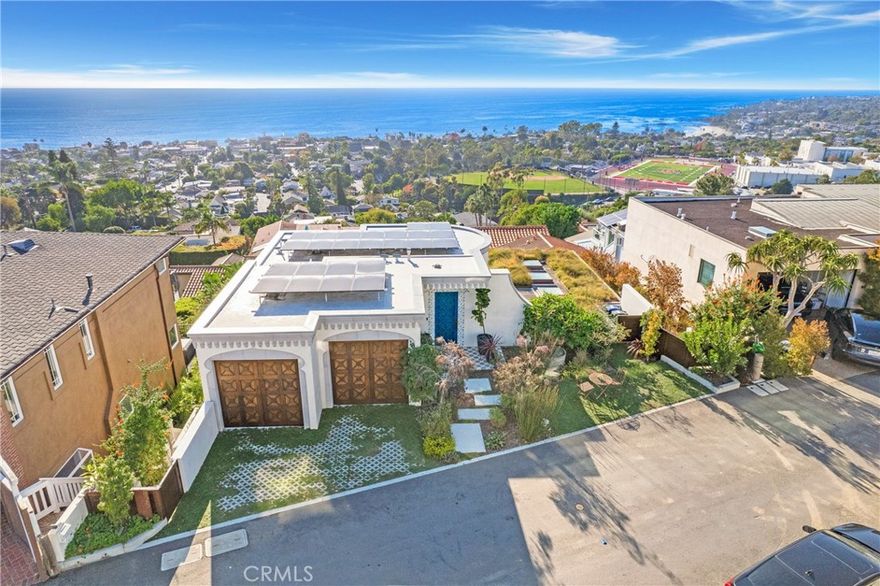 Incredible opportunity for this stunning ‘newer’ construction residence, perfectly positioned to capture panoramic ocean views & offering a wonderful blend of contemporary design with Moroccan-inspired elegance. Designed to maximize indoor/outdoor living, the residence offers multiple outdoor spaces perfect for year-round enjoyment. Enter at street level & be drawn to breathtaking views of the ocean, Catalina Island and Main Beach Laguna through oversized picture windows. The ‘retreat style’ Primary suite crowns the top floor and features a fireplace, spa-like ensuite with walk-in shower, freestanding tub & balcony to enjoy panoramic views. The main level, accessed by a graceful curved staircase adorned with custom ironwork & hand-blown glass by a local artisan, is designed for entertaining. Hardwood oak flooring, smooth stucco walls, and Moroccan-inspired light fixtures create a space with skylights and a fireplace clad in handmade Zellige tile. The bright living area opens through French doors to a spacious ocean-facing balcony. The adjacent chef’s kitchen impresses as the centerpiece of the main living space with leathered soapstone countertops, copper accents including hammered range hood & farm sink, a 48” ILVE range, walk-in pantry, prep sink, and generous counter space make this kitchen both functional and beautiful. A unique library/den space off the main living includes a bespoke fireplace with mosaic tiles and carved wood surround, custom millwork, and an ocean-facing bay window seat offering a perfect spot to relax while enjoying the view. This space could also serve as a home office or bedroom, with ensuite access to a full bathroom. A main-level bedroom affords the option as a primary suite with walk-in closet and ‘Jack & Jill’ bathroom featuring a soapstone vanity, dual copper sinks, and custom tiled shower. On the lower level, a 3rd bedroom with ensuite offers a private oasis, with outdoor access to the secluded covered patio/sundeck with Arto tile flooring, Zellige tile fountain, gas fire-pit, custom mosaic ‘art’ wall, fruit trees, herbs, seasonal Morel mushrooms & vibrant, water-wise landscaping. No detail has been overlooked in this exceptional home, incorporating eco-conscious features such as owned solar power, two EV charging stations, extra-dense insulation, a green roof and ductless mini-split systems for energy-efficient climate control. This residence offers an unparalleled opportunity to experience coastal living at its finest.