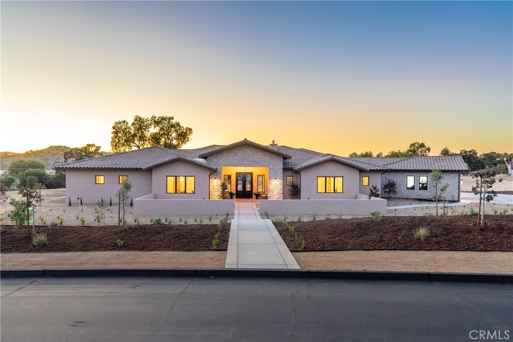 Located within the exclusive guard-gated community of Santa Ysabel Ranch, this brand-new single-level residence offers a rare combination of luxury, privacy, and the Central Coast lifestyle. Residents enjoy unmatched amenities including 24-hour security, tennis and pickleball courts, and miles of scenic walking trails. Spanning approximately 4,155 square feet, the thoughtfully designed floor plan features three bedrooms, a dedicated office, three and a half bathrooms, a three-car garage and approved plans for an ADU. The landscaped front yard sets the tone, while the expansive backyard offers endless potential to create your dream outdoor oasis. A grand entry welcomes you into the stunning living room where vaulted ceilings with exposed beams, a gas fireplace, and sliding pocket doors create a seamless indoor to outdoor living experience onto the covered patio complete with its own fireplace for year-round enjoyment. The gourmet kitchen is a showstopper with two oversized islands each with prep sinks, bar seating, a wine fridge, high-end appliances, and designer finishes. A dedicated built-in wine display and bar area elevate the entertaining space, while the spacious walk-in pantry adds function and convenience. The luxurious primary suite features a private patio, a spa-inspired bathroom with dual sinks, a freestanding soaking tub, a custom-tiled shower, and a generous walk-in closet. The family room, connected through the double-sided living room fireplace, offers additional gathering space with comfort and style. Showcasing exceptional craftsmanship, designer finishes, and unmatched privacy, this home is an extraordinary opportunity to own in one of Paso Robles’ most coveted communities while still having the freedom to design your ultimate backyard retreat.