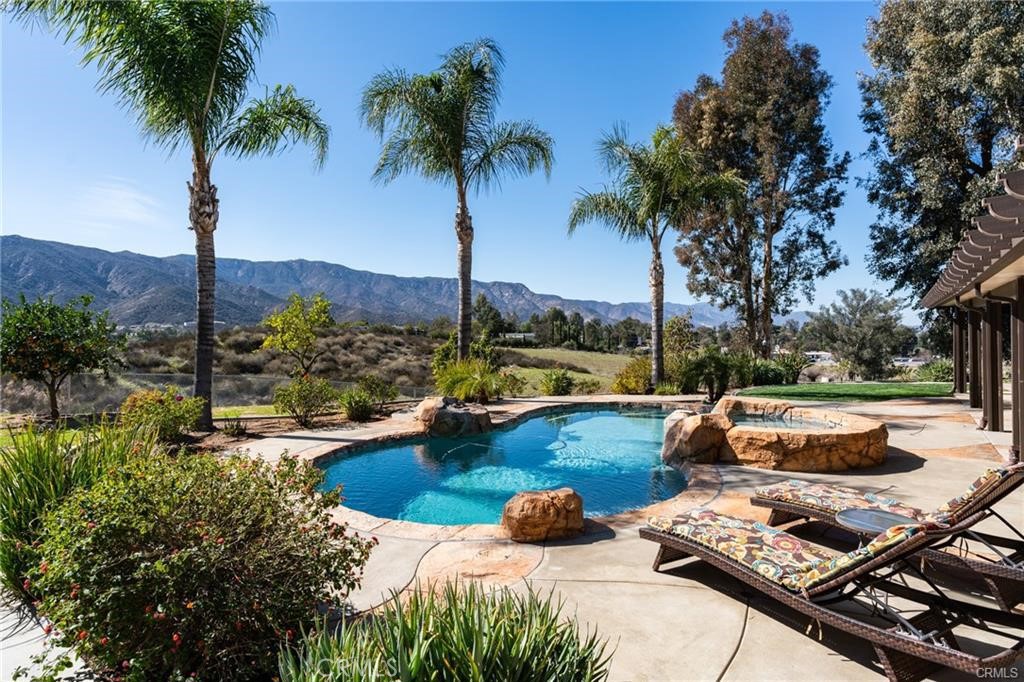 Single story home in Wildomar with a 280 degree panoramic view with mountains to the west and rolling hills to the east.
The remodeled kitchen features a large center island, granite counters, and custom cabinetry. The primary suite is spacious, and both bathrooms have been recently remodeled. A home office is conveniently located just off the dining and living rooms.
The backyard is designed for entertaining with a pebble tech pool with beach entry and reef, spa, covered patio, and an outdoor BBQ area with a wood fired pizza oven. Additional improvements include an above ground garden with sink and an insulated 12’ x 24’ metal storage shed.
The 1.37 acre lot is fully fenced with RV parking and hookups. Property is serviced by both well water and city water. This home has an incredibly LOW TAX RATE of 1.03%