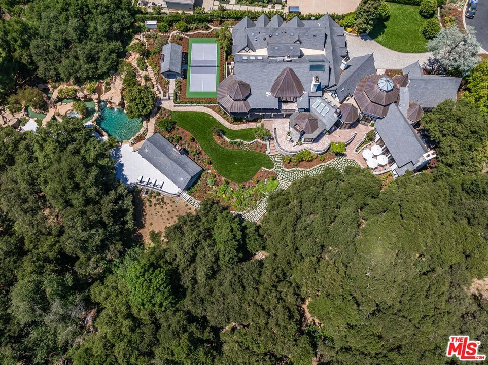 Spanning over 15,000 square feet on over 2 private acres, this estate sits within the gated enclave of Island Forest, surrounded by the fairways of North Ranch Country Club. Originally designed by a Disney collaborator known for immersive environments, it was later purchased by the current owner, who completed a meticulous 2.5-year, down-to-the-studs renovation. Step inside to find soaring ceilings, rich materials and curated living spaces that balance scale with comfort. The foyer features a dramatic installation of 1850s stained-glass panels sourced from a historic European church, chosen for their color, detail and artistry casting a prismatic glow across the entry. The primary suite is a private retreat with a sitting lounge and fireplace, a resort-style bath with sculptural soaking tub and large walk-in shower. A boutique dressing room with built-ins and a generous closet area. The five additional bedroom suites are equally luxurious, each with its own distinct layout, bespoke finishes and spa-quality en-suite baths. These guest suites rival those found in the finest resorts, offering both comfort and privacy for family and guests. A two-story elevator provides seamless access to both levels. Six additional powder rooms are strategically positioned to complement the home's flow and support effortless entertaining. The estate offers four kitchens: a chef's kitchen, prep kitchen, butler's kitchen and a full kitchen in the pool house. The chef's kitchen also includes a separate dining area, offering a comfortable space for informal meals or gathering during meal prep. The main living room features a walk-in fireplace and a built-in kitchen/bar, creating a warm and inviting environment ideal for entertaining. Additional spaces include a gym, temperature-controlled wine cellar, hair and makeup salon, library and a birds-eye writing nook. The movie theater features professional projection and sound. A dedicated entertainment room serves as the ultimate performance lounge, complete with a built-in stage ideal for private performances or live music. A billiards room with fireplace adds a casual gathering area and a sound-insulated podcast studio supports content creation, interviews or virtual meetings. These spaces offer function, privacy, and creative flexibility. Distinguishable highlights include 11 fireplaces (9 with Carrara marble mantels), 12 chandeliers on motorized hoists, wide-plank wood floors, a stained-glass ceiling in library, Perrin & Rowe fixtures, and custom cabinetry. Tucked within its own oak-shaded enclave, the pool and spa feel like a hidden retreat surrounded by towering trees that filter golden light and lend an air of serenity. Designed for resort-style enjoyment, it includes waterfalls, a winding lazy river, and an elevated spa at its center. A custom slide is built into the hardscape. The grounds also include outdoor dining and lounge spaces, plus a full pool house with kitchen and living area, perfect for indoor-outdoor lifestyle.Other features include a pickleball court with a covered lounge and fireplace, lush landscaping and multiple fruit trees. Features dedicated parking for 10 cars, complemented by additional abundant guest parking. Behind the scenes, the home is equally well-equipped. A Nice Home Management system controls lighting, climate, shades, media, surveillance and pool/spa systems. Major upgrades include a DaVinci composite slate roof with copper turrets, custom steel windows and doors, 9 HVAC systems operating across 21 zones, and a dedicated control room centralizes all systems, ensuring seamless access for monitoring and maintenance. An estate of this scale, design, and quality is rarely available - offering a rare combination of architectural vision, modern innovation, and resort-caliber amenities in one of Southern California's exclusive enclaves.