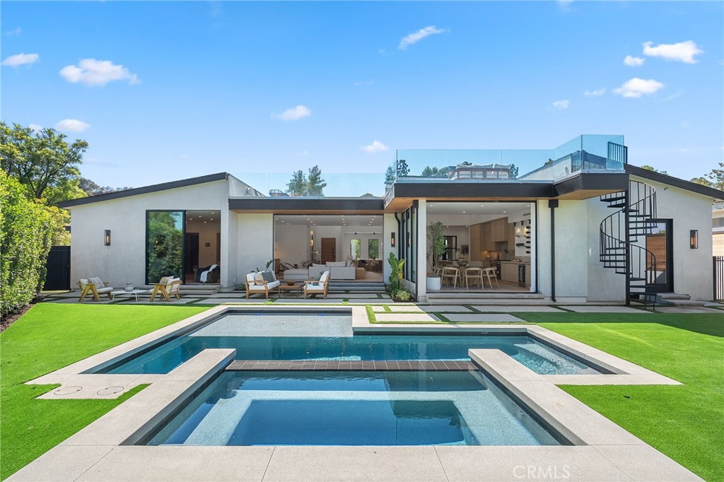 Perched high above the Valley in the hills of Encino, resides this stunning newly reimagined and luxurious estate that offers dramatic city light views. Situated on a gated quarter-acre lot, this home features a contemporary exterior that gives way to a warm, inviting interior filled with rich woods, natural stone and high-end fixtures. The bright and airy open-concept floor plan is anchored by a gourmet chef’s kitchen equipped with top-of-the-line Thermador smart appliances and a massive waterfall island with a built-in table. Both the spacious living room and formal dining room boast oversized sliding glass doors that disappear into the wall, seamlessly extending your living space outside so you can take full advantage of indoor-outdoor living. A true entertainer’s paradise, the private backyard retreat offers a resort style pool with a large spa and baja shelf, a poolside cabana and expansive 874 square foot rooftop patio – the perfect place to start your day as you watch the sun rise over the Valley. Inside, you’ll find four generously sized ensuite bedrooms, including a luxe primary suite that features dual walk-in closets and a sumptuous bathroom, complete with an oversized rainfall shower, soaking tub and double vanity. Additional highlights include a home office, dedicated laundry room, high ceilings throughout, a smart home system with built-in speakers and a two-car garage. Located South of the Boulevard within the top-rated Lanai School District, this exceptional property enjoys easy access to everything the Valley and Westside have to offer.
