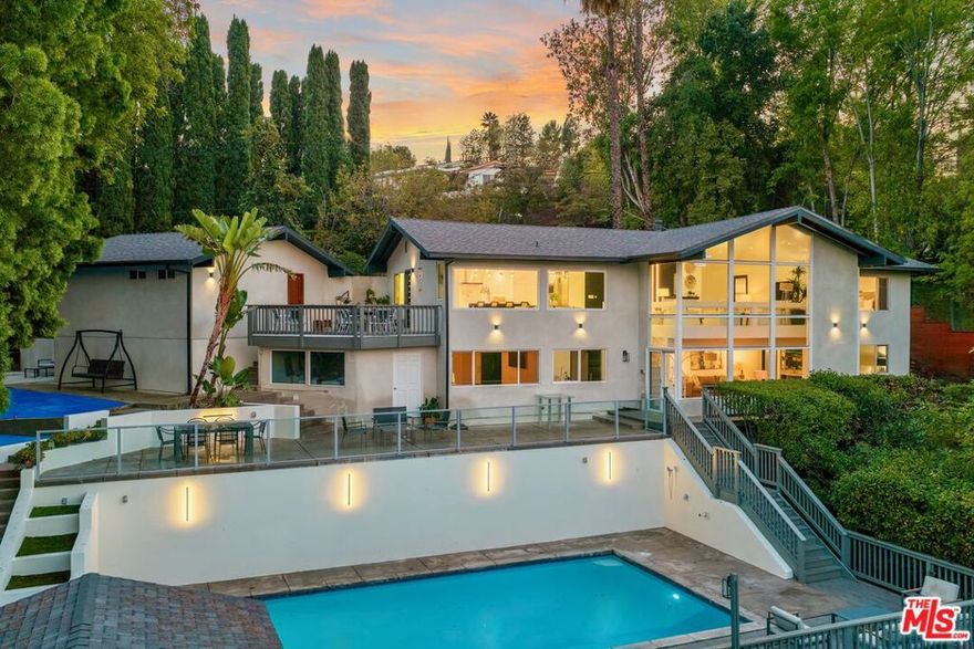 Ideally situated south of the boulevard in one of Tarzana's most coveted hillside enclaves, this ultra-private, fully remodeled California Contemporary is hidden behind a long gated driveway and invisible from the street, truly one of Tarzana's best-kept secrets. Spanning 2,752 square feet of interior living on a 0.55 Acre usable lot, this home is an entertainers paradise with seamless indoor/outdoor living across three levels, with a massive pool, stunning valley views and a completely private backyard. Every detail has been meticulously reimagined, from the smooth Venetian-plastered walls and LED-lit stairways to the chef's kitchen outfitted with sleek custom cabinetry, Wolf and Thermador appliances, and designer finishes throughout. The main level features an open-concept living and dining area with walls of glass framing sweeping vistas, an elegant powder room, and a stunning primary suite with a spacious walk-in closet and spa-inspired bath complete with heated floors and exquisite materials. Downstairs, discover three additional bedrooms, including a secondary primary suite with its own en-suite bath, plus a second full bath, a family room with built-in wet bar, and generous storage, making the home ideal for hosting, guests, or multi-generational living. Outside, the property unfolds into a true entertainer's paradise: multiple lounging and dining terraces, a massive heated pool and hot tub, expansive deck space, and a large fenced backyard with endless potential for ADUs, sport courts, or custom outdoor living spaces. Additional highlights include a fully automated smart-home system, two-car garage, ample gated parking, and exceptional privacy throughout. A rare blend of modern design, scale, and seclusion, this Tarzana hillside retreat embodies the very best of Southern California living.