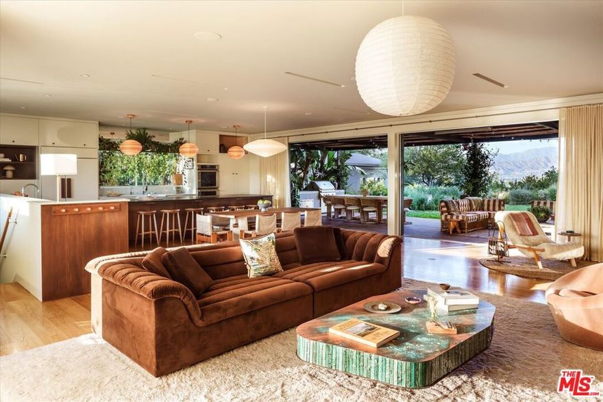 Set behind gates and a long private driveway, the Sunswept Compound by architect Barbara Bestor, with a recent refresh by Swike and gardens by Judy Kameon of Elysian Landscapes, is an exceptionally private modern-ranch retreat set on more than half an acre. With sweeping mountain views, a flat grassy yard, pool, spa, and detached guest house, the property embodies the spirit of LA living--architectural pedigree, seamless indoor-outdoor flow, and layered, artful detail. A private and gated landscaped approach leads to the residence, where the signature open living space unfolds. Recently restored by its current owner, the living room, dining area, and chef's kitchen--anchored by a substantial island--extend through pocketing Fleetwood doors to the outdoor dining terrace, lounge, and separate outdoor kitchen. Quintessentially Californian, this is indoor-outdoor living at its best. Flooded with natural light from skylights and expansive windows, the home is equally suited for intimate gatherings or large-scale entertaining, with multiple spaces to socialize around the fire pit, pool, gardens, or outdoor fireplace. The spacious primary suite offers a sizable closet and en-suite bath, with Fleetwood doors that frame lush gardens and open directly to the cedar soaking tub and outdoor shower. On the opposite wood-paneled wing, three guest bedrooms await: a private guest suite featuring an en-suite 3/4 bathroom, as well as two additional bedrooms with a shared full bath. The lower level offers a generous informal living room, ideal as a den, playroom, or screening room. The detached bonus structure on the property features a kitchenette and  bath, providing flexible space for visitors or an at-home office. A third structure, a separate pool house, features a sauna, 3/4 bath, and additional storage. Rounding out the grounds are two separate and distinct areas for vegetable gardens, mature trees throughout, and parking for more than six cars. Sunswept is at once private, pedigreed, and deeply livable--an extraordinary creative compound designed for both entertaining and everyday life, just moments from Erewhon, Equinox, and the best Ventura Boulevard has to offer.
