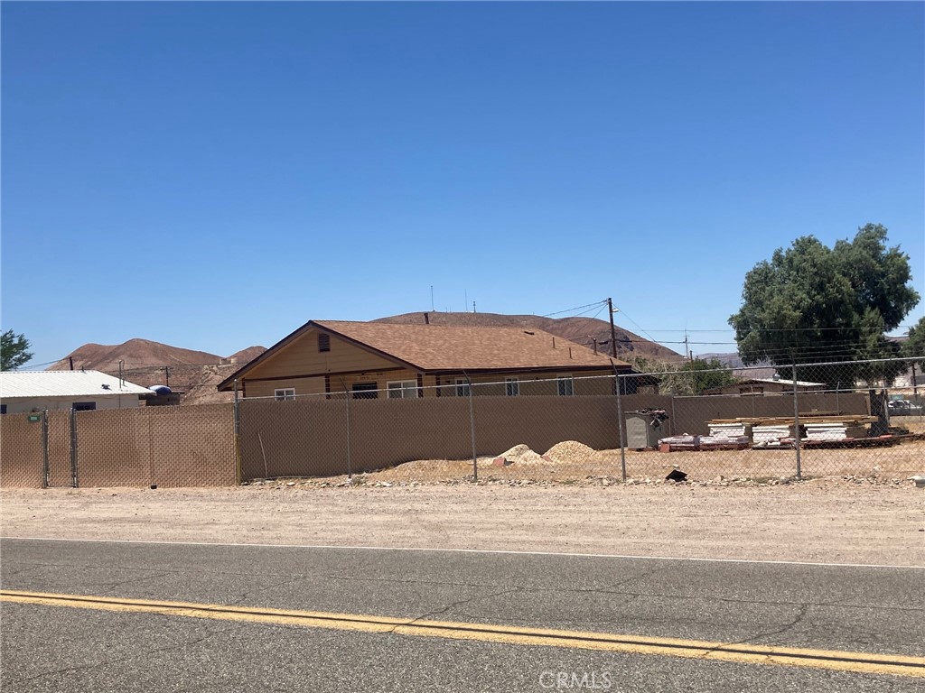 Super cute home in Daggett, it's built in 1985 so newer than most in the area. And the large fenced lot adjoining to the east, and the boxcar on it are included!!! The two lots together total almost 1/2 acre. Both the home and the extra lot are fully fenced with chain link, some with privacy fencing. Windows are dual pane. The home is 1036 s/f, with two bedrooms, 1 3/4 bathrooms. The main bedroom is large and has a walk in closet. Kitchen has lots of cabinets, a snack bar, range oven & microwave. Living room includes a great cabinet for TV, storage, displays, etc. Home is partially furnished and Seller says all the furniture and appliances stay. Inside the front fence is a little courtyard that helps block wind & gives privacy at front door. In the back there is an attached screened in porch plus a huge open patio area at back. Each side of the home has separately fenced areas which would be perfect for dog run on one side, garden on the other. New shingle roofing installed in 2023. Why such a low price for all this home has to offer? Because Seller is hoping for a quick cash sale in existing condition, which actually seems to be quite good, appears to have had lots of love & care.