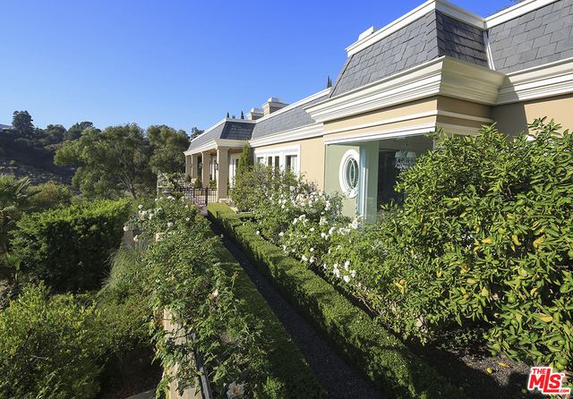 This sumptuous French Regency-style Bel Air estate radiates elegance. With panoramic city views, it is impeccably crafted. There are two beautifully appointed kitchens. The master suite, with fireplace and French doors to a secluded patio, has a luxurious bath and serene views. The lower level has an entertainment room, fitness space, sauna, wine room, and private guest suite. An elevator serves all levels. Grounds include formal gardens, pool, wraparound terrace, and a superb rooftop view deck.