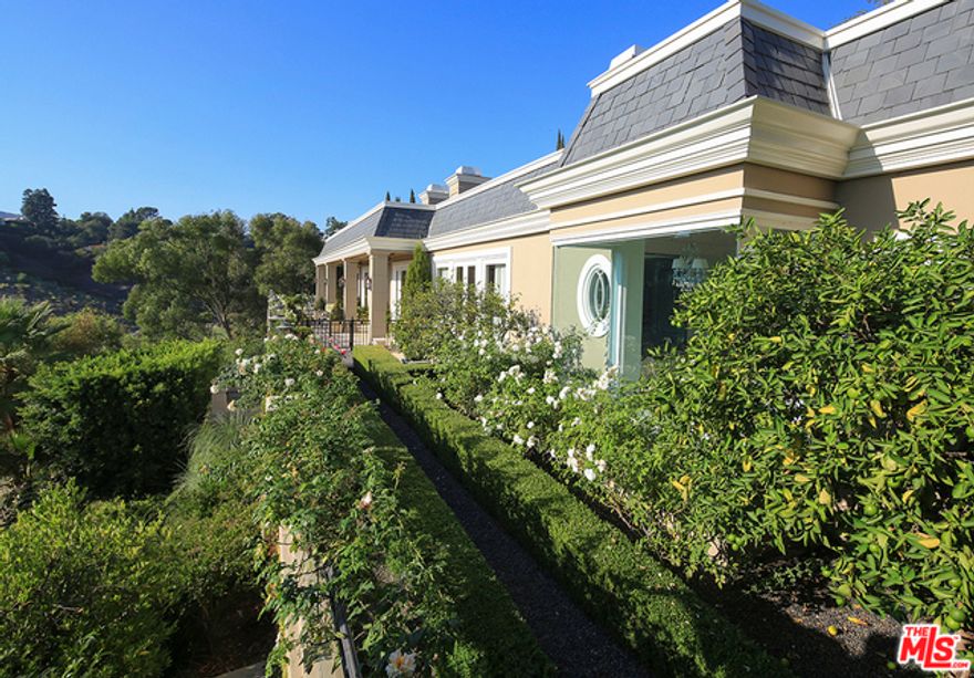 This sumptuous French Regency-style Bel Air estate radiates elegance. With panoramic city views, it is impeccably crafted. There are two beautifully appointed kitchens. The master suite, with fireplace and French doors to a secluded patio, has a luxurious bath and serene views. The lower level has an entertainment room, fitness space, sauna, wine room, and private guest suite. An elevator serves all levels. Grounds include formal gardens, pool, wraparound terrace, and a superb rooftop view deck.