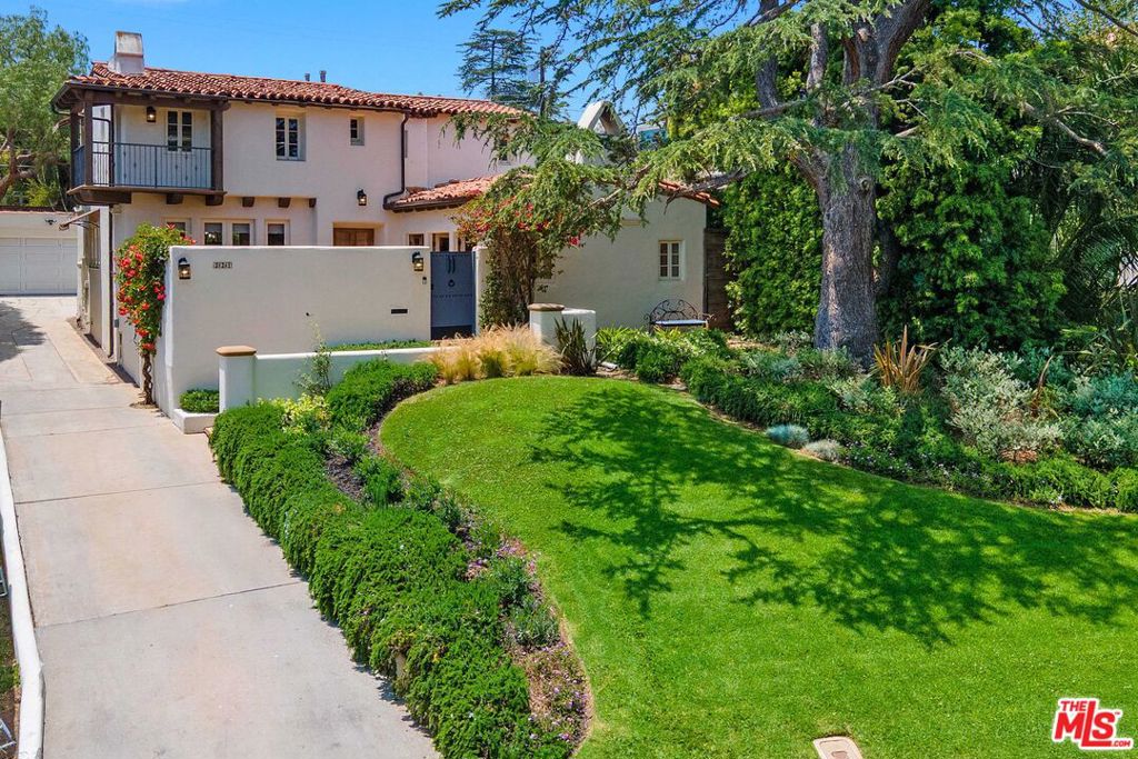 This beautiful and authentic 1927 Spanish Revival home is ideally located on one of Brentwood's most sought-after streets, blending old-world charm with modern comfort, luxury, and privacy. Beyond the gated, character-rich courtyard, the home makes an immediate emotional impression with its antique front door and timeless architectural integrity. Inside, exquisite craftsmanship is on display - imported tiles, ebony wood floors, distressed wood beams, and custom millwork are just a few of the many design details that evoke a deep sense of warmth and history. The living room features soaring cathedral ceilings with exposed wood beams, a stately fireplace, and built-in cabinetry that enhances both form and function. The thoughtful floor plan includes three bedrooms and three bathrooms - two upstairs and one downstairs with direct access to a tranquil patio. Each bedroom offers decorative fireplaces and generous built-in storage. The stately primary suite also features two walk-in closets, a private balcony, and a large bathroom with a separate tub and shower. Designed for a seamless indoor-outdoor lifestyle, the home offers multiple outdoor spaces for entertaining and relaxing, including a romantic front courtyard and a spacious backyard with a striking blue-tiled spa as well as a BBQ and al fresco dining/lounge areas. The detached garage is finished with an epoxy floor and built-in cabinetry. Located just minutes from Brentwood's best shops, restaurants, cafs, and the beloved Farmers Market, this is a rare opportunity to own a soulful and meticulously cared-for residence.