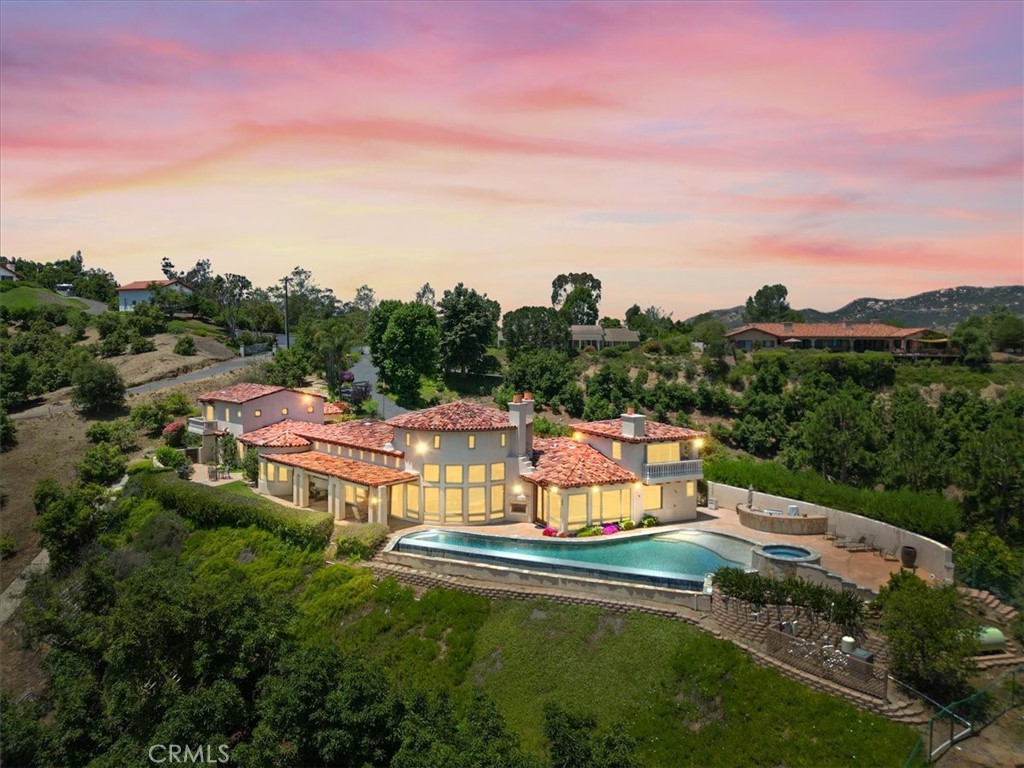 Discover luxury and craftmanship in this breathtaking Tuscan-inspired estate set of 6.37 private acres overlooking the Santa Margarita River Valley. The main residence offers 5,751 sq ft of living space, complemented by a 780 sq ft guest apartment featuring 2 bedrooms and 1 bath - perfect for visitors or extended family.
Step inside to soaring exposed beam ceilings, travertine flooring and dramatic floor-to-ceiling windows that showcase the views and flood the home with natural light and frame the views of the infinity-edge pool, rolling hills and canyon beyond.
The open concept floor plan flows seamlessly from the elegant great room to the dining area and into the gourmet kitchen. The chef's kitchen is a true showpiece, featuring top-of-the-line appliances, granite counters, custom cabinets, pendant lighting and walk-in pantry. The adjoining breakfast room opens to a covered patio - perfect for morning coffee or entertaining al fresco.
A private primary suite offers a luxurious spa-like bath with soaking tub, dual vanities and his and hers closets. Get the morning workout done in the private gym located in the adjacent loft area.
This exceptional residence offers an expansive layout with each additional bedroom featuring an en-suite private bath. The executive office is perfect for remote work with wood finishes and custom built-ins. For the wine connoisseur, the home includes a personal wine room custom cabinetry to showcase your finest vintages.
The 6.87 acres includes a professionally managed avocado grove and a 3.63 acre building site, a rare opportunity to expand or create a family compound.
Located in Edgewater Estates a gated community of custom homes this property is just minutes from downtown Fallbrook but worlds away from ordinary.