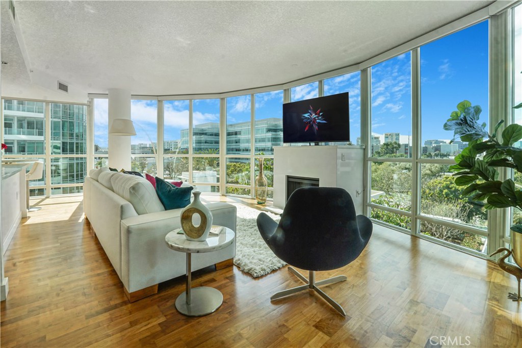 Modern Elegance - Discover the epitome of luxury living in this alluring residence nestled in one of Orange County's most prestigious high-rises, Marquee Park Place. Located on the 5th floor, this unit has undergone beautiful upgrades including a sleek modern flushed quartz countertop & backsplash effortlessly blending an open-concept layout with modern sophistication inviting comfort. Panoramic views throughout massive curved windows and a floating white quartz fireplace view of abundant city lights, sunsets and manicured gardens below lend a beautiful backdrop to this serene one story residence when entertaining guests or enjoying the evening view. Featuring a versatile and innovative custom-designed Murphy bed that seamlessly transforms into a functional desk. This dual-purpose furniture piece is ideal for maximizing utility without sacrificing style. Embellish luxury high-rise living in a rare highly desirable end unit offering a circular floor-plan boasting two bedrooms, two baths, balcony, open gourmet kitchen with European styled cabinetry, reimagined quartz breakfast bar, elegant wine cooler, stainless steel appliances, brand-new refrigerator, solid hardwood floors and in-unit washer/dryer. Situated in a 24-hour guard-gated community with concierge service, residents have access to top-notch amenities, including a pool, spa, gym, billiards room, and lounge. Perfectly positioned, just minutes from Fashion Island, South Coast Plaza, and a host of fine dining options at Park Place. In- addition this location offers unbeatable freeway access. The HOA covers water, trash, gas, and internet, with no Mello Roos fees. This is luxury redefined—schedule your tour today!