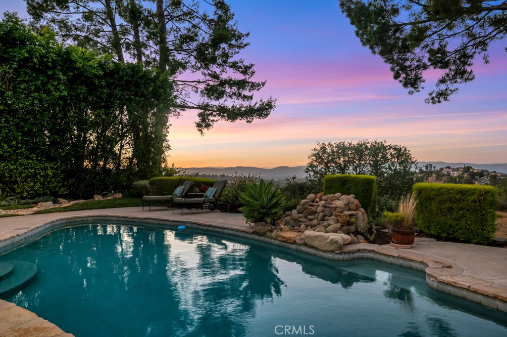 Perched in the tranquil hills of Woodland Hills and nestled within the sought-after Woodland Crest Estates, this beautifully updated 4-bedroom, 3-bathroom residence offers 2,397 square feet of refined living space on a generous 10,068 square foot lot. Surrounded by the breathtaking backdrop of the Santa Monica Mountains, this private oasis combines luxurious comfort, modern upgrades, and incredible outdoor living—just minutes from The Village, Malibu beaches, and top-rated Woodland Hills Elementary School. A Zen-like front yard with lush, mature landscaping welcomes you with a sense of calm and seclusion, creating privacy from the street. Inside, the inviting living room features a cozy fireplace, a charming bay window that fills the space with natural light, and built-in surround sound for an elevated experience. The recently remodeled chef’s kitchen boasts quartz countertops, stainless steel appliances, a peninsula for casual dining, and flows seamlessly into the formal dining area—perfect for gatherings of any size. The spacious primary suite offers dual closets, direct access to the yard, and a spa-like bath with a glass shower and dual vanity. Step outside into your entertainer’s dream backyard, where you'll find a sparkling pool, a large covered patio with integrated surround sound, and a built-in outdoor BBQ—ideal for al fresco dining, weekend entertaining, or simply relaxing in a peaceful, private setting surrounded by greenery and serene mountain views. Additional highlights include new carpet in guest bedrooms, fresh interior and exterior paint, a two-car garage, and thoughtful updates throughout. This is a rare opportunity to own a true hillside gem that effortlessly blends style, space, and the ultimate California lifestyle.