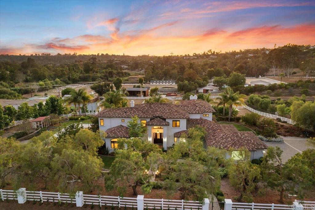 Properties like this simply don't come by very often! A newer custom built estate, with perfect South and West exposure, on a FLAT 1 acre private lot, in the sought-after West side of Olivenhain! Built in 2011 by a commercial contractor for his own family, the property borders the magnificent Olivenhain horse trail system, and offers panoramic sunset views, westerly breezes and has room for the ultimate in entertaining. Featuring multiple fruit and citrus trees, raised veggie garden beds, the "Rolls Royce of chicken coops" and an Olympic-size sand volleyball court, this property caters to the active lifestyle. If volleyball is not your thing, the south facing yard can easily be converted to allow for a pickleball court, a large grassy area for playing games, and a new POOL. There is room to add an ADU (2 possible locations) - but you may not need to as the current layout of the house offers the perfect guest suite, with its own private entrance already. The gated property is on a private tree lined street and is the perfect 'trail head' for hiking or biking the renowned Spooks Canyon and its winding river trail. The custom home features soaring ceilings throughout that create an ambiance of grandeur and space, with a junior primary suite downstairs and an elegant over sized second level primary suite. The heart of the home is the great room featuring a large kitchen island ideal for both meal preparation and casual dining, along with top-of-the-line Wolf double ovens, a gourmet Wolf gas range, and a Sub Zero fridge/freezer. Flowing seamlessly from the kitchen is the inviting family room, complete with a stacked stone fireplace and sweeping views, ideal for relaxed gatherings or intimate moments. From the dining room, French doors open to the back patio for al fresco dining! A optional bedroom/office completes the downstairs. Upstairs you'll find two secondary bedrooms, a huge open loft and a flex room that could also serve as a bedroom with a small modification. Convenience meets luxury with whole house water filtration, a mudroom (with a DOG SHOWER), laundry room and the 3-car garage that easily fits an oversized truck (approx 30 feet in depth), providing ample storage and functionality for modern living. The home lies in the acclaimed Olivenhain Pioneer Elementary school district and provides easy access to the shopping and restaurants in Encinitas just minutes away.