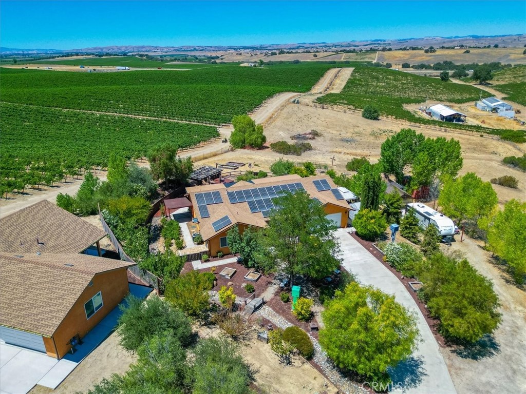 Nestled among picturesque vineyards is this stunning1,654± sq. ft. custom-built main house and a newly constructed 807 ± sq. ft. accessory dwelling unit (ADU, built in 2023) offer privacy on a serene two-acre lot. The main home welcomes you with beautifully landscaped grounds and a spacious entry porch. Set back from the road, it features an extended concrete driveway and additional RV parking. Inside the main house, vaulted ceilings, solid natural wood doors, and durable vinyl plank flooring create an inviting atmosphere. The expansive kitchen boasts granite countertops, a large island with a solid walnut surface, and includes appliances. Windows in the family room, kitchen, dining area, and primary bedroom frame breathtaking vineyard views. The primary bedroom offers a flexible layout, currently connected to the adjacent middle bedroom for added space. Reconfiguring the hallway doors can easily restore it as a separate third bedroom. Smart home features control lighting, ceiling fans, and heating and air conditioning for modern convenience. The attached two-car garage includes 220V power for an electric vehicle charger. A covered back patio provides ample space for relaxation and features an outdoor kitchen. The side yard, adjacent to the primary bedroom, is pre-wired with 110V power for a future spa. The ADU mirrors the main home’s quality with a living room, a generous kitchen featuring Corian countertops and includes appliances, vinyl plank flooring, and vaulted ceilings. It includes a spacious bedroom with a walk-in closet and a three-quarter bathroom. It also has an attached two-car garage with laundry facilities and an electric vehicle charger. Its covered porch/patio overlooks the neighboring vineyard, enhancing its charm. Both homes are equipped with an owned solar electric system, central heating and air conditioning, and include refrigerators and washers and dryers. The property also features a 20± ft. SeaTrain storage container, a wood shed, and a greenhouse, making it an ideal retreat for versatile, modern country living.