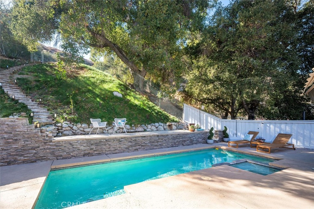 Discover Serenity in this Stunning Upgraded Entertainer’s Pool Home, ideally situated at the end of a Cul-de-Sac in the Highly Sought-after Rancho La Salle Gated Community. Set on over 1 acre, this Exquisite Ranch Style Home Offers a Semi-Custom feel with a Designer’s Touch throughout, High Ceilings and a Tranquil Setting that Feels like a Private Mountain Retreat. As you enter the Impressive Formal Entry you are welcomed by soaring Cathedral Ceilings and Romantic Fireplace in the expansive Living Room. The thoughtfully Designed Floor Plan Features 3 Large Bedrooms, 2 Bathrooms (One Remodeled), Formal Dining Area with Newer Sliding Doors to the Resort Style Backyard. The Heart of the Home is the Spectacular Gourmet Kitchen, featuring a Huge Quartz Island with Pendant Lighting, Subway Tile Backsplash, Plenty of Cabinets, Lots of Counter Space a Cozy Breakfast Nook leading to the Private Serene Backyard Oasis with Shimmering Pool & Spa. Perfect for the Celebrity Chef! The Master Bedroom Boasts Newer Sliding Doors that open to a Peaceful Outdoor Area & Upgraded En-Suite Bathroom. Large Secondary Bedrooms with Newer Mirrored Closet Doors & Closet Organizers. Features include: Upgraded Flooring, Recessed Lighting, Stunning Light Fixtures, Newer Electrical Panel, Newer Pool & Spa Heater and Tesla Charger. Professionally Hardscaped & Landscaped. Truly Unique Resort Style Backyard with Glimmering Pool, Spa and Outdoor Shower. Several areas to Relax and Enjoy the Scenery. The Perfect Sanctuary for Entertaining and Family Gatherings! 2 Car Garage with Finished Walls, Recessed Lighting, Epoxy Flooring & Professionally Painted. Super Clean (Could be used as a Gym).Some photos have been virtually staged. Large Driveway with Custom Pavers. Close to Towsley Canyon, Ed Davis Park, Award Winning Schools, Shopping and Easy Freeway Access. No Mello Roos. This One-of-a-Kind Home is the Perfect Private Sanctuary for Entertainers, Families, or those seeking a Peaceful Lifestyle in a Prestigious Location.