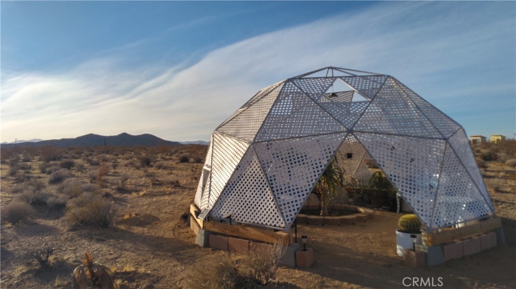 5 Acres in Landers with panoramic views and several unique greenhouse and camping structures as well as an outhouse already there! This could be your opportunity to own your own little piece of the desert and spend the night under the stars, toasting marshmallows over the fire pit surrounded by native vegetation and the tranquil sounds of the desert night. This is your perfect hi desert base camp! Local? Hop on the opportunity to have your own plant nursery to propagate cactus or whatever your heart desires. Homes already in the area, though the property doesn't currently have utilities. Address is fictitious, no address has been assigned to the property.
