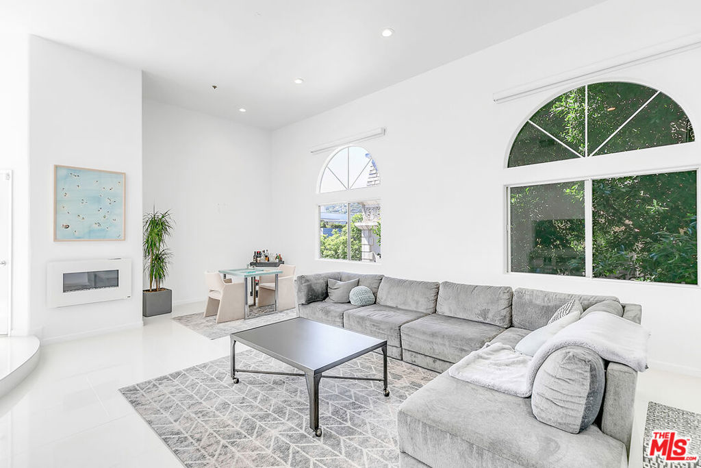 Steps from Melrose Place, this renovated penthouse boasts soaring ceilings, floor-to-ceiling windows, and sweeping views of the Hollywood Hills and West Hollywood skyline. The open layout is filled with natural light and features sleek white porcelain tile and upgraded flooring. A gourmet kitchen with quartz countertops, modern cabinetry, and stainless steel appliances opens to the living area. The spacious primary suite offers a walk-in closet and spa-like bath with a jetted tub and luxury shower system.