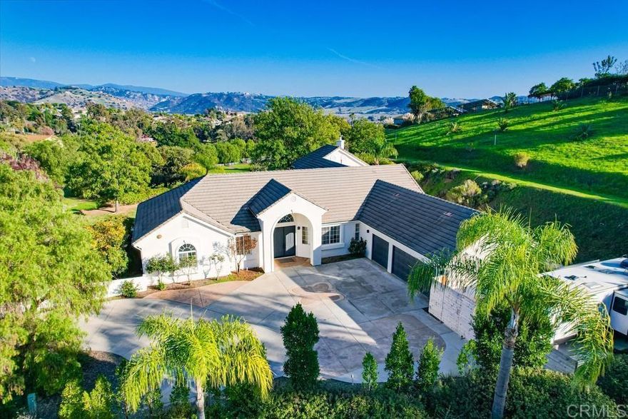 Seller will entertain offers between $1,550,000 - $1,650,000. VA assumable loan at 2.875% interest rate. Tucked at the end of a private, tree-lined road and surrounded by rolling hills, this 2.35-acre estate offers a sense of peace that’s increasingly rare. Here, panoramic views, elevated finishes, and your own small private vineyard create an inviting backdrop for everyday living. This turnkey property has been thoughtfully refreshed with new interior and exterior paint, 5" baseboards, new doors, upgraded flooring, modern light fixtures, a gas fireplace, premium bathroom finishes, and a stunning La Cantina door in the foyer/living room that frames mountain views to the east. The spacious layout includes 4 bedrooms (1 is an optional bedroom/office), and a generous primary suite featuring an ensuite bath and walk-in closets. Outdoors, the property is just as captivating, with a charming gazebo, working fountain, pergola-covered patio, producing fruit trees (avocado, peach, lemon, loquat, apple, pomegranate, fig & grapefruit) and multiple seating areas spread across two adjacent lots. Both lots are flat/genltly sloped and usable - a rare find in this area! A 3-car garage with epoxied flooring and gated RV pad offer ample room for vehicles, toys, and gear. All of this is offered with quick access to Hwys 76 and 15, near the Golf Club of California and Fallbrook wineries including the upscale Monserate Winery, AND less than 30 minutes to Oceanside beaches and Camp Pendleton.